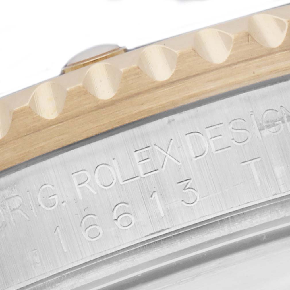 The image shows a close-up of the side of a Rolex Submariner 16613 Men
s Steel and Gold (two tone) Blue Dial with visible bezel teeth and engraved case details.