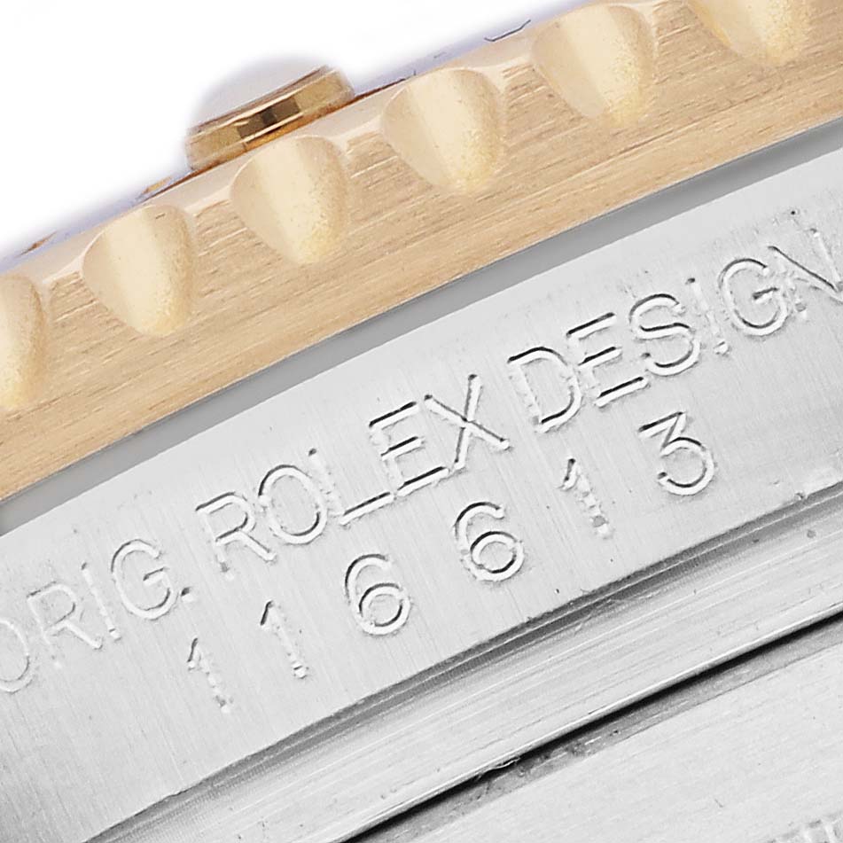 The image shows a close-up of the bezel and engraved edge of a Rolex Submariner 116613 Men
s Steel and Gold (two tone) Blue Dial.