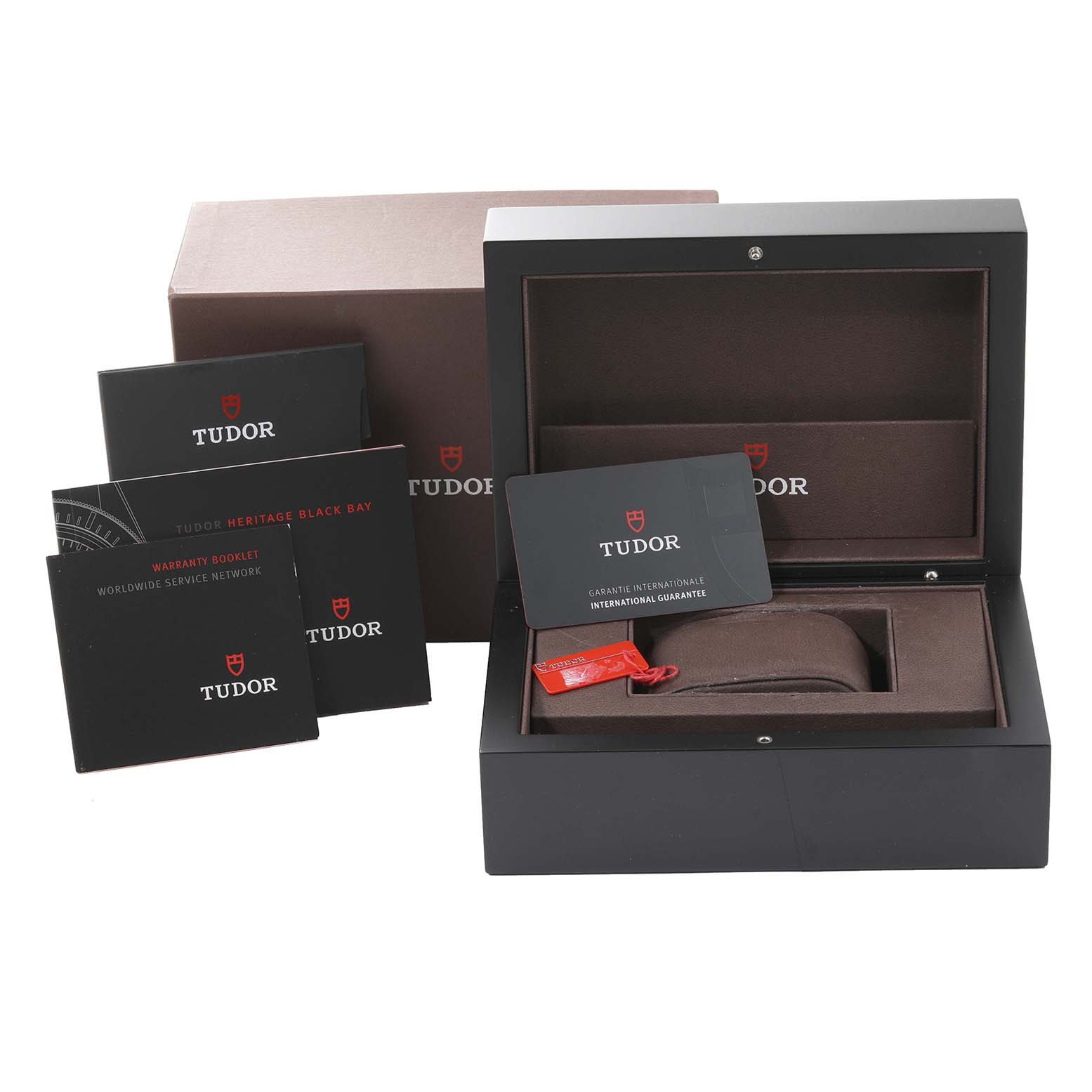 The image shows the packaging and accessories for the Tudor Heritage Black Bay 79220R Men
s Stainless Steel Black Dial 79220R Men
s Stainless Steel Black Dial, including the box, booklets, tag, and guarantee card.