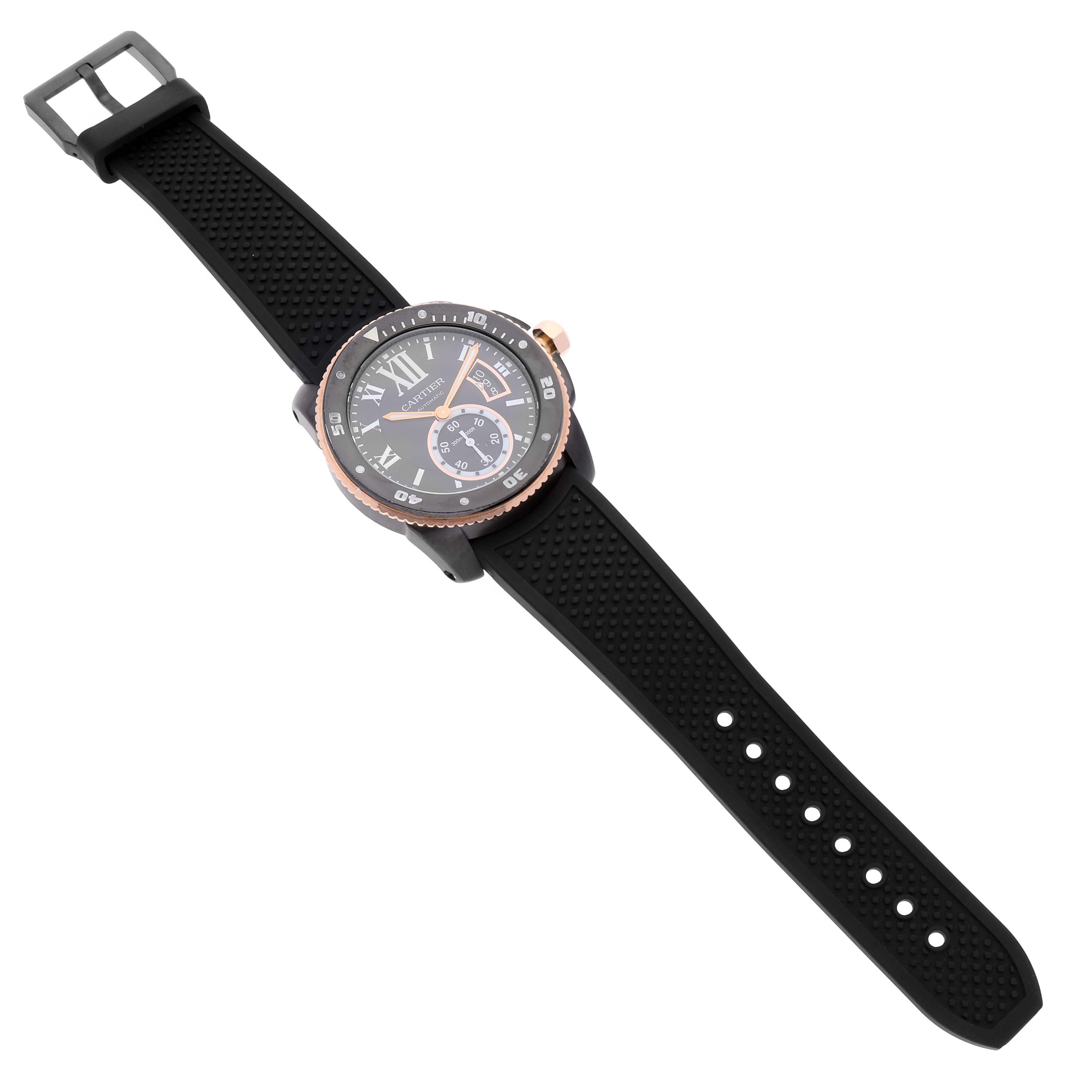 The image shows a top-down view of a Calibre de Cartier watch by Cartier, featuring a black rubber strap and a detailed face.