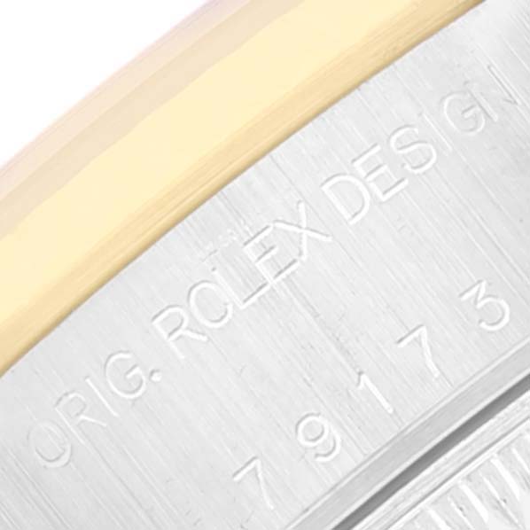 This image shows a close-up of the Rolex Datejust 79173 Women
s Steel and Gold (two tone) White Dial 79173 Women
s Steel and Gold (two tone) White Dial watch case edge with engraved text.