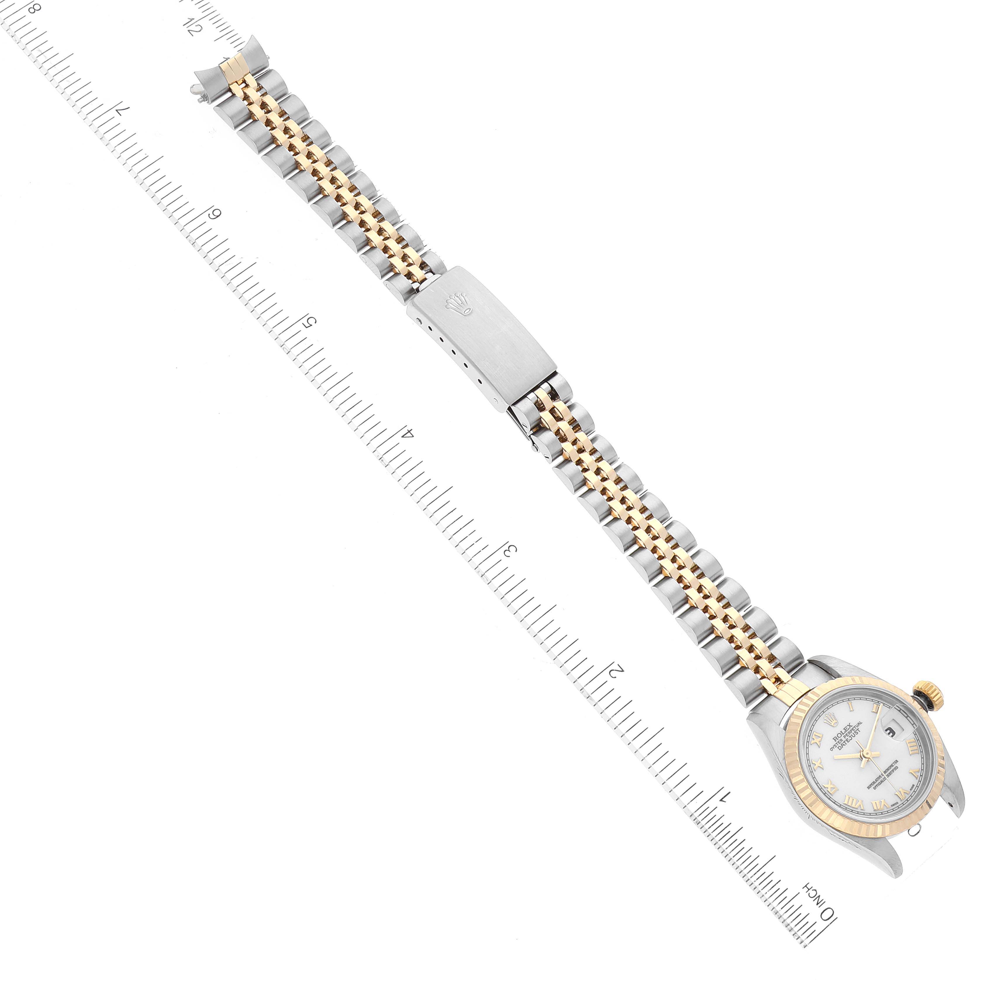 The image shows a top view of a Rolex Datejust 79173 Women
s Steel and Gold (two tone) White Dial 79173 Women
s Steel and Gold (two tone) White Dial watch, highlighting its bezel, dial, and two-tone bracelet with a clasp.