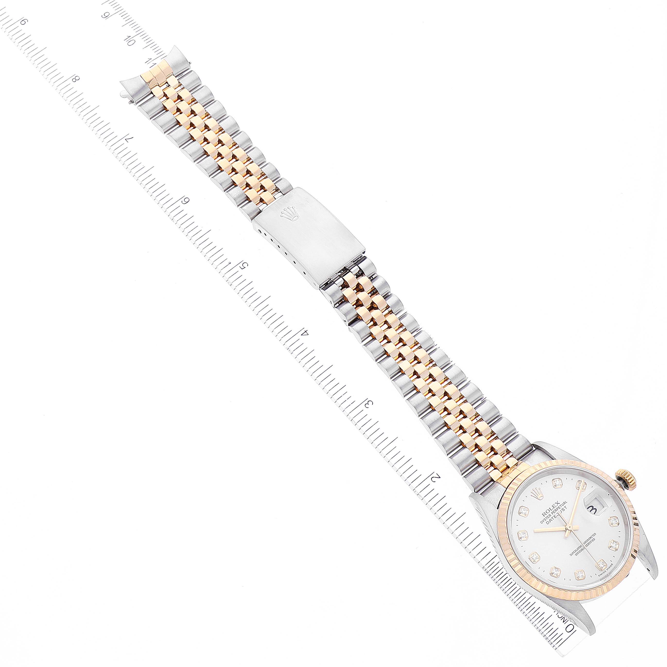 The Rolex Datejust 16233 Men's Steel and Gold (two tone) Silver Dial 16233 Men's Steel and Gold (two tone) Silver Dial watch is shown from an overhead angle featuring its dial, two-tone bracelet, and clasp with a ruler for scale.