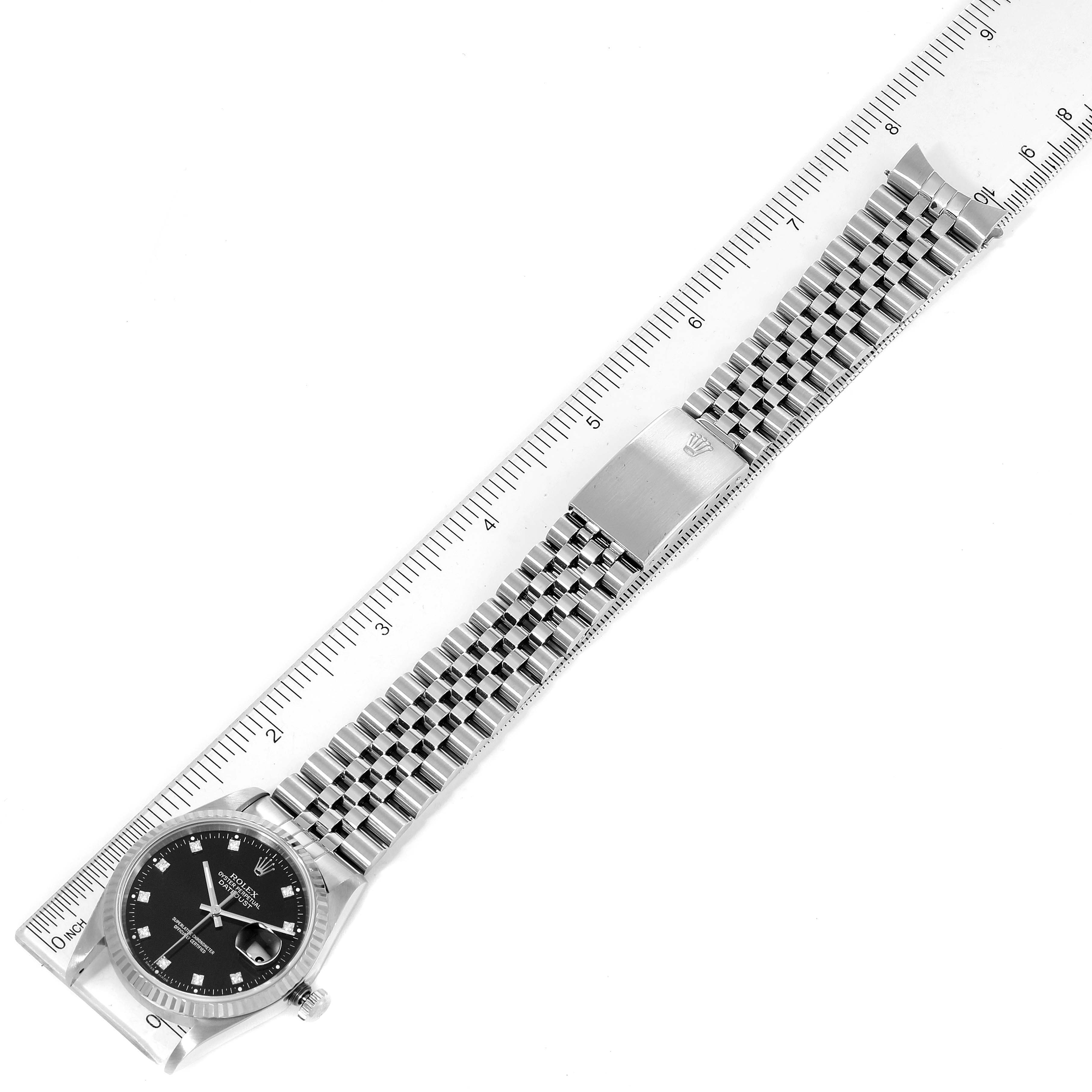 The image shows a top-down view of a Rolex Datejust 16234 Men
s Stainless Steel Black Dial 16234 Men
s Stainless Steel Black Dial watch, displaying the case, dial, and the full metal bracelet next to a ruler.