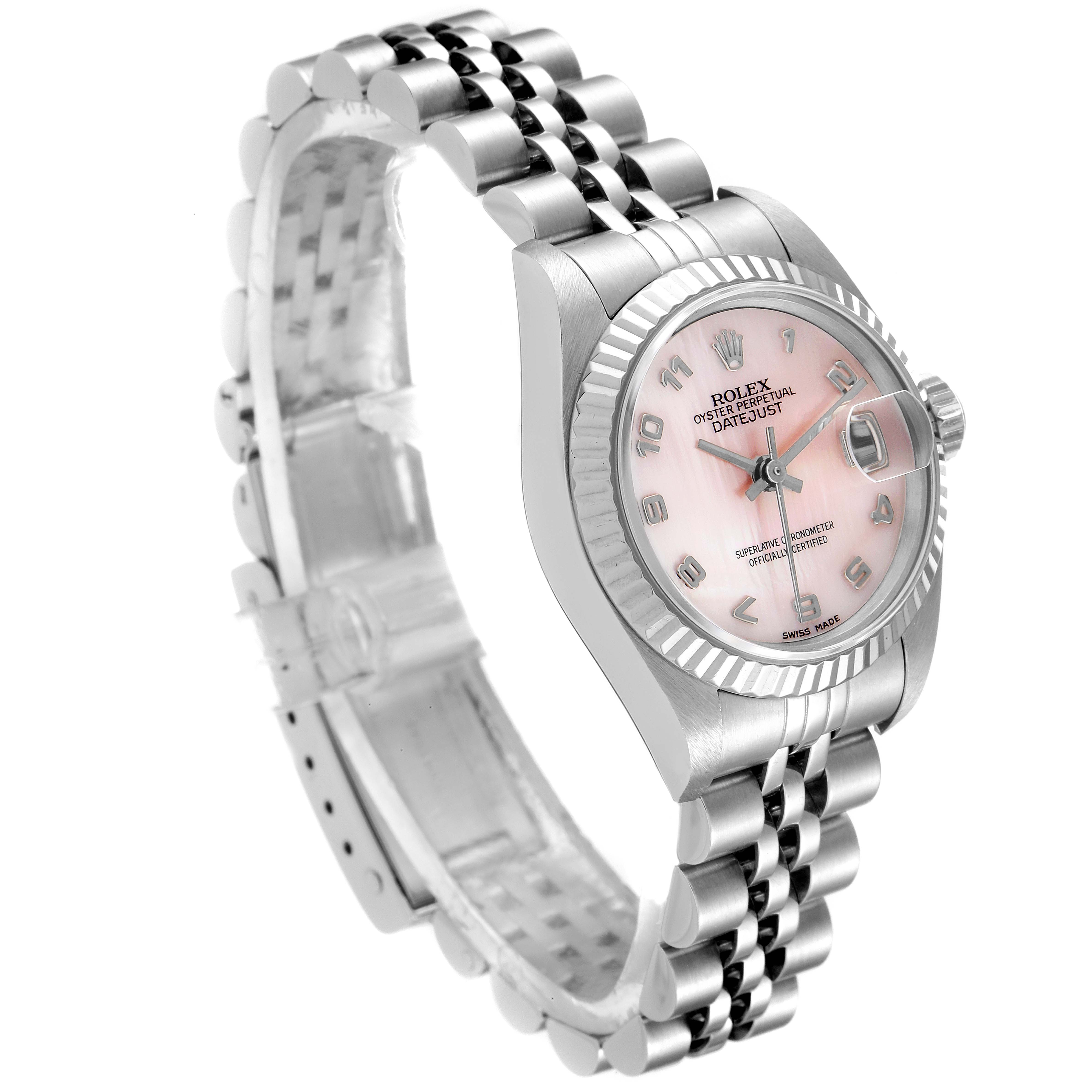 The image shows an angled view of a Rolex Datejust 79174 Women
s Stainless Steel Mother of Pearl Dial 79174 Women
s Stainless Steel Mother of Pearl Dial watch, highlighting its pink dial, fluted bezel, and Jubilee bracelet.