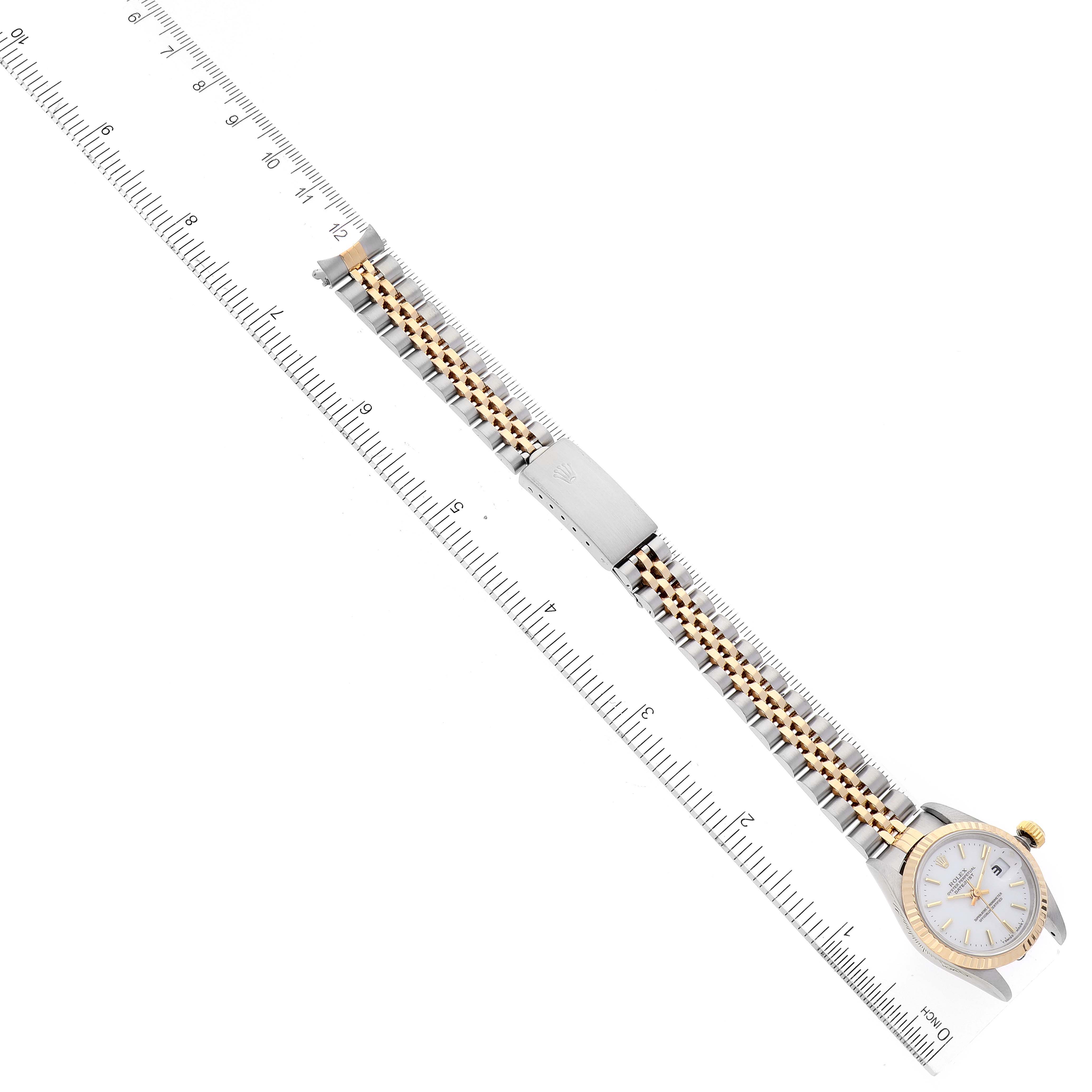 The image shows a top view of a Rolex Datejust 69173 Women
s Steel and Gold (two tone) White Dial 69173 Women
s Steel and Gold (two tone) White Dial watch, with the face, bezel, and two-tone bracelet visible alongside a ruler for scale.