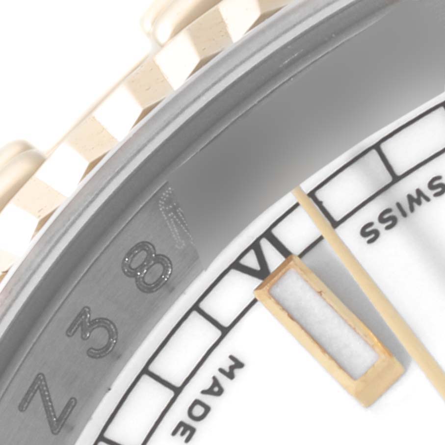 This close-up image of a Rolex Datejust 116233 Men's Steel and Gold (two tone) White Dial 116233 Men's Steel and Gold (two tone) White Dial watch shows part of the dial, the minute marker, and the serial number engraving.