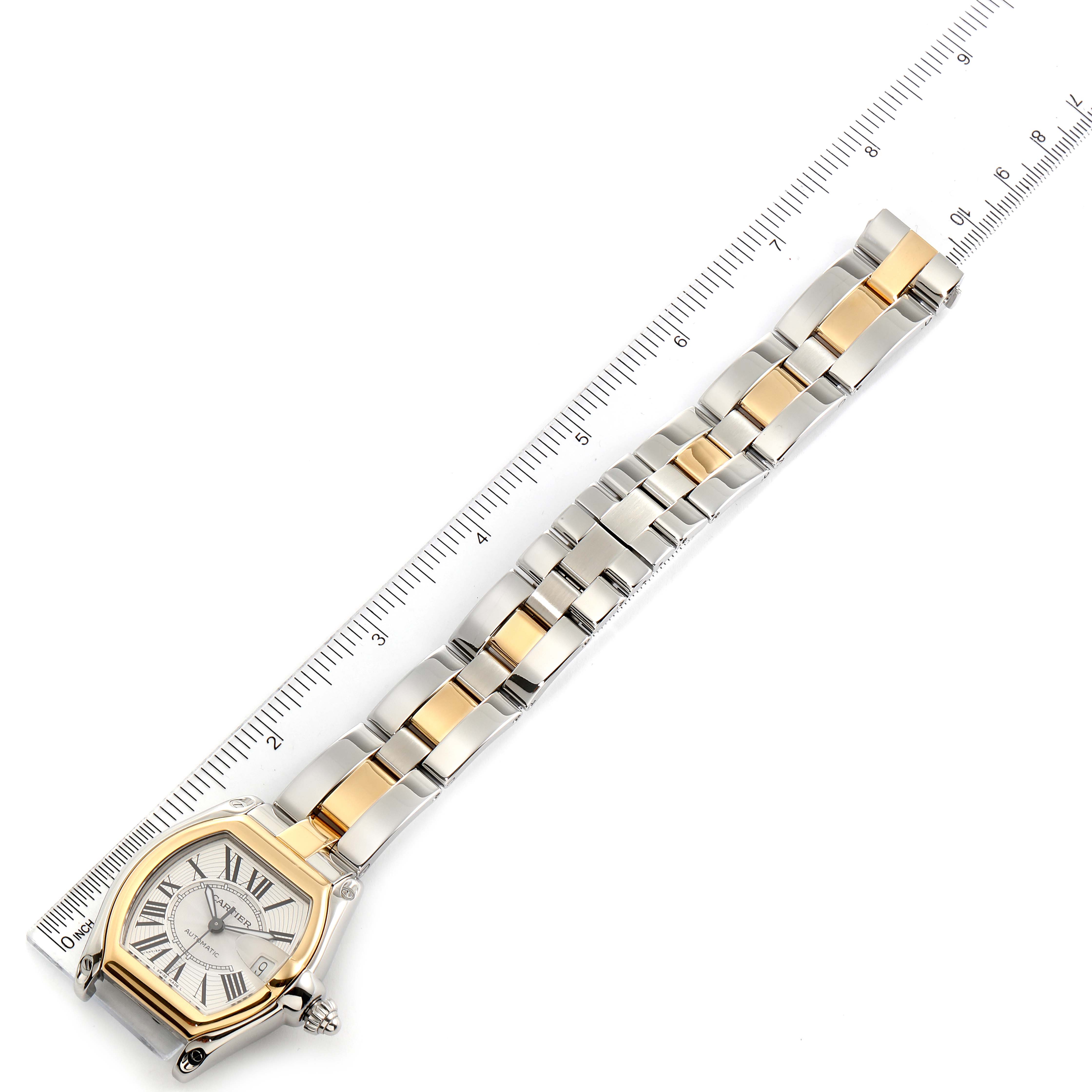 This image displays a top-down view of a Cartier Roadster W62031Y4 Men's Steel and Gold (two tone) Silver Dial W62031Y4 Men's Steel and Gold (two tone) Silver Dial watch with its entire face and bracelet shown against a ruler.