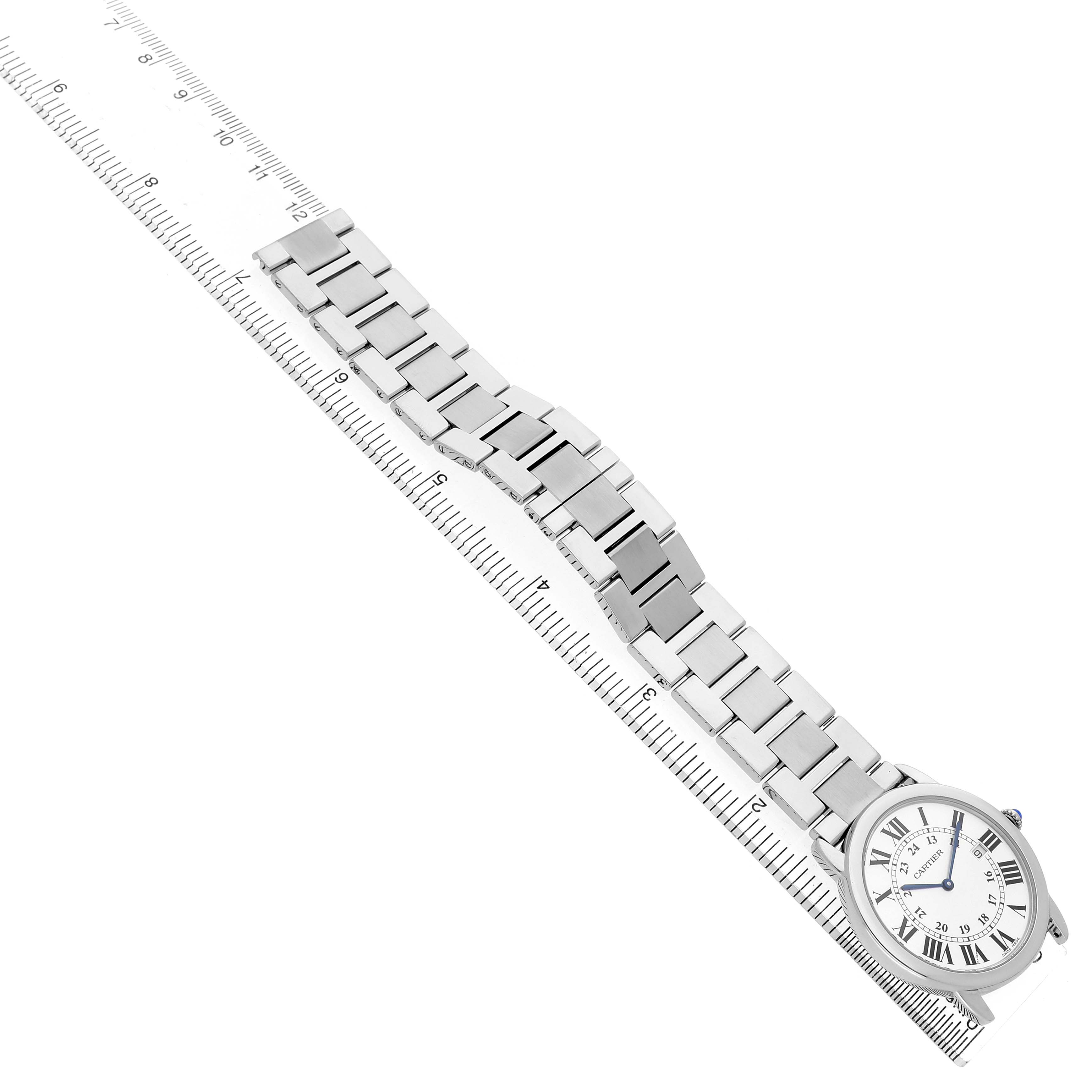 The Cartier Ronde W6701005 Men's Stainless Steel Silver Dial watch is shown from a top-down angle, displaying the face and metal bracelet alongside a ruler.
