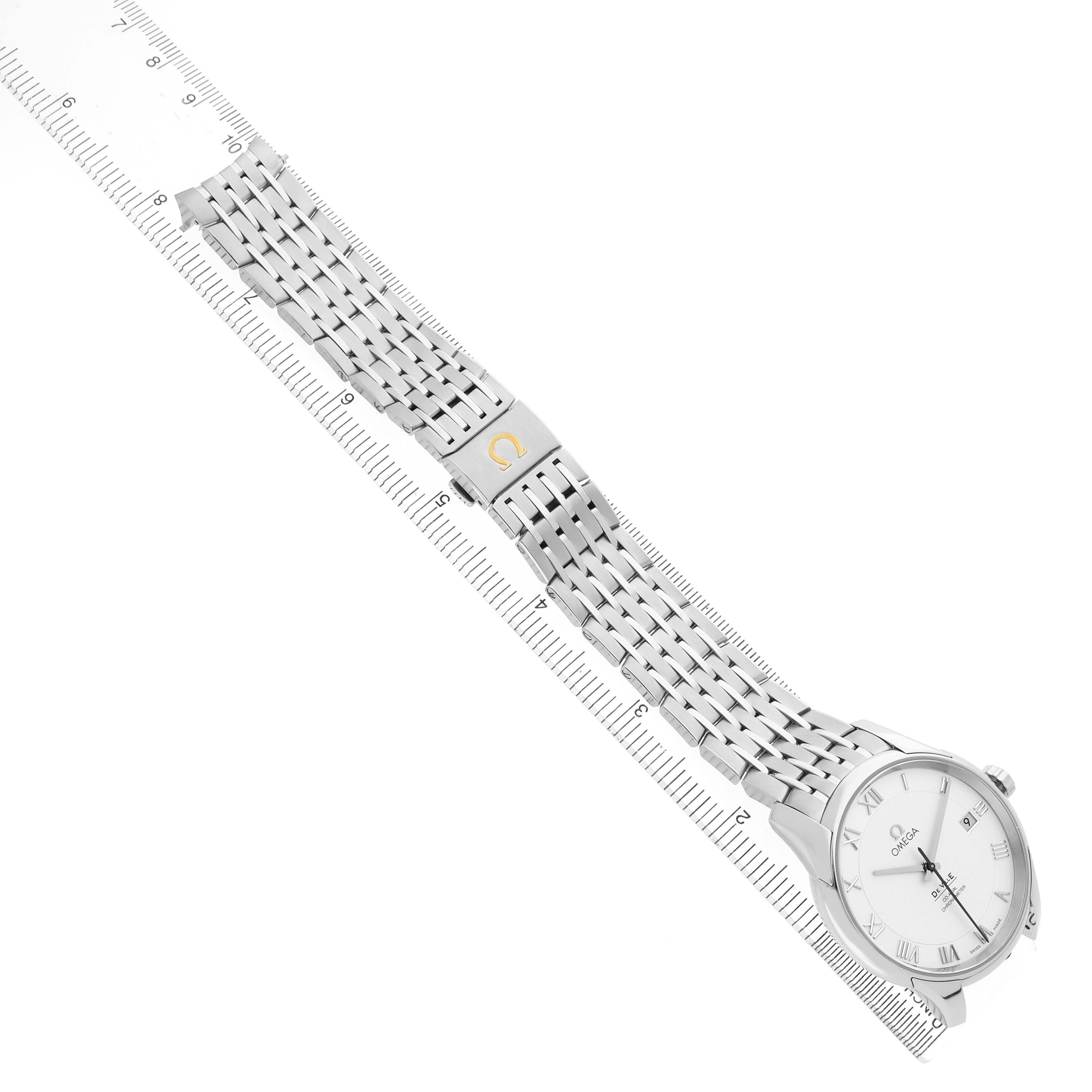 The Omega De Ville 433.10.41.21.02.001 Men's Stainless Steel Silver Dial watch is shown from a top-down angle, displaying its face, bracelet, and clasp on a ruler.