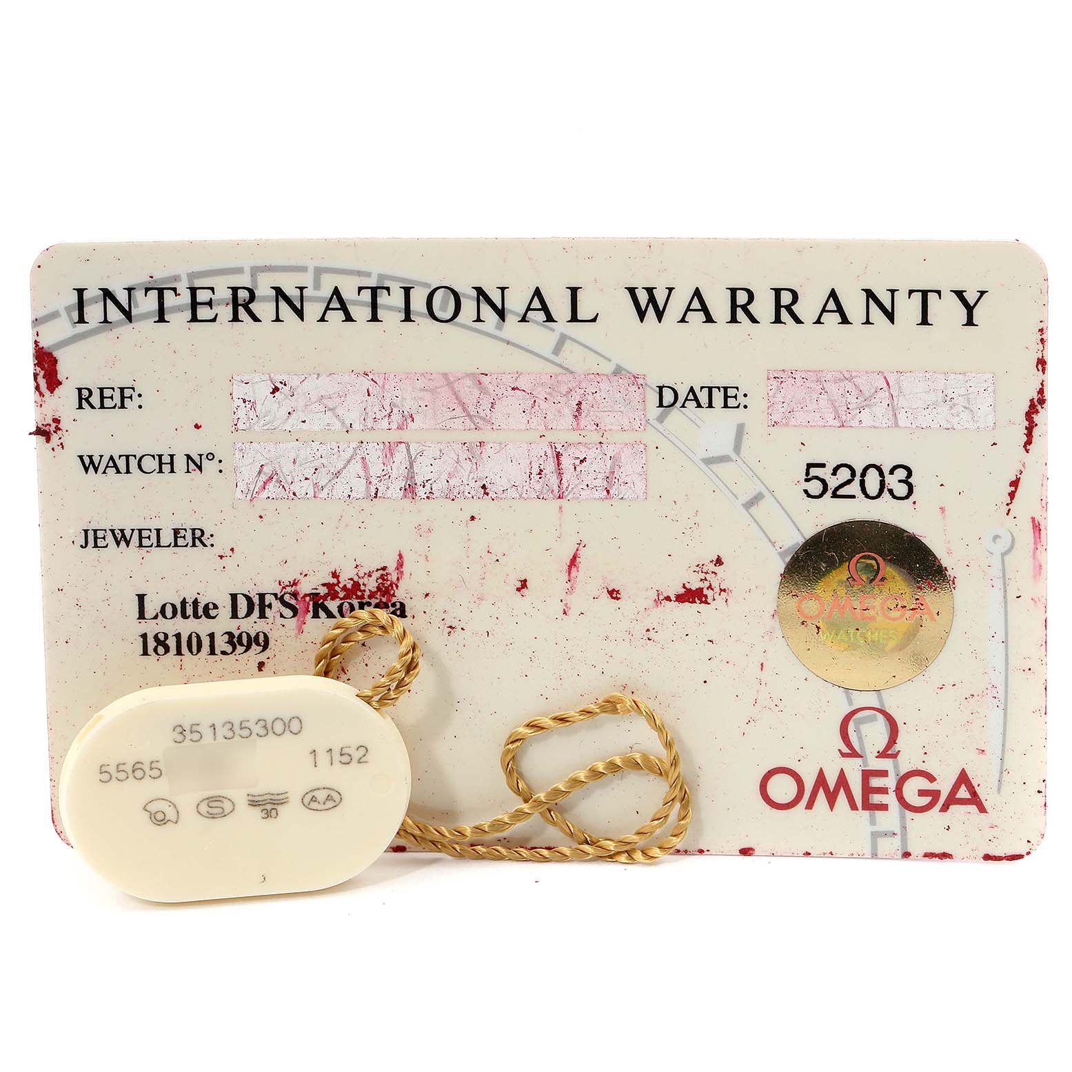 The image shows an Omega Speedmaster 3513.53.00 Men
s Stainless Steel Black Dial 3513.53.00 Men
s Stainless Steel Black Dial International Warranty card and a tag with a gold-colored string.