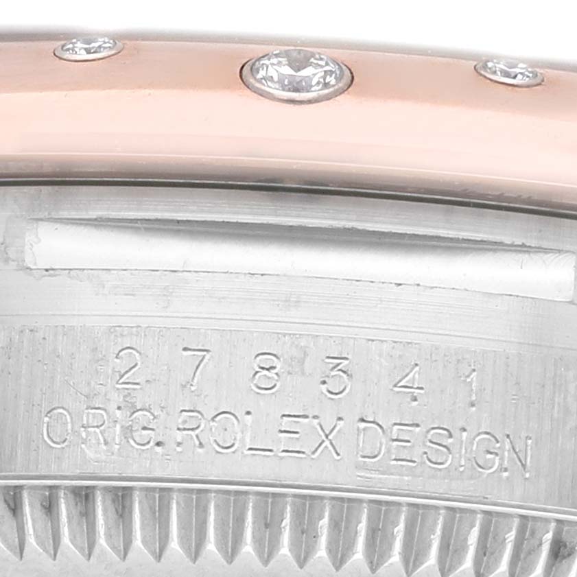 The image shows a close-up of the bezel and case side of a Mid-Size Rolex watch, featuring diamond accents and engraving.
