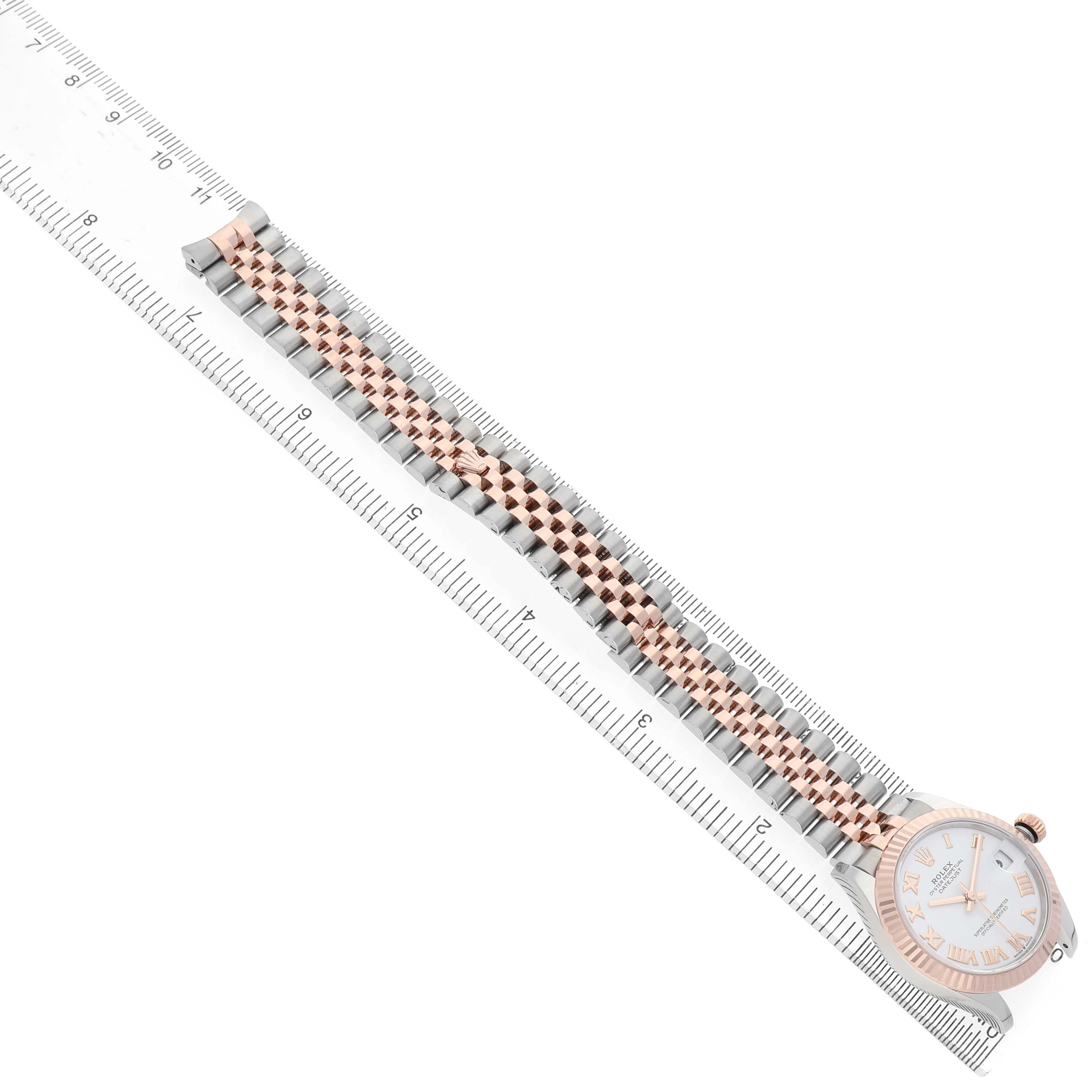 The Rolex Mid-Size 278271 Women's Rose Gold White Dial watch is shown from a slightly elevated angle, displaying the full bracelet, dial, and bezel next to a ruler for scale.