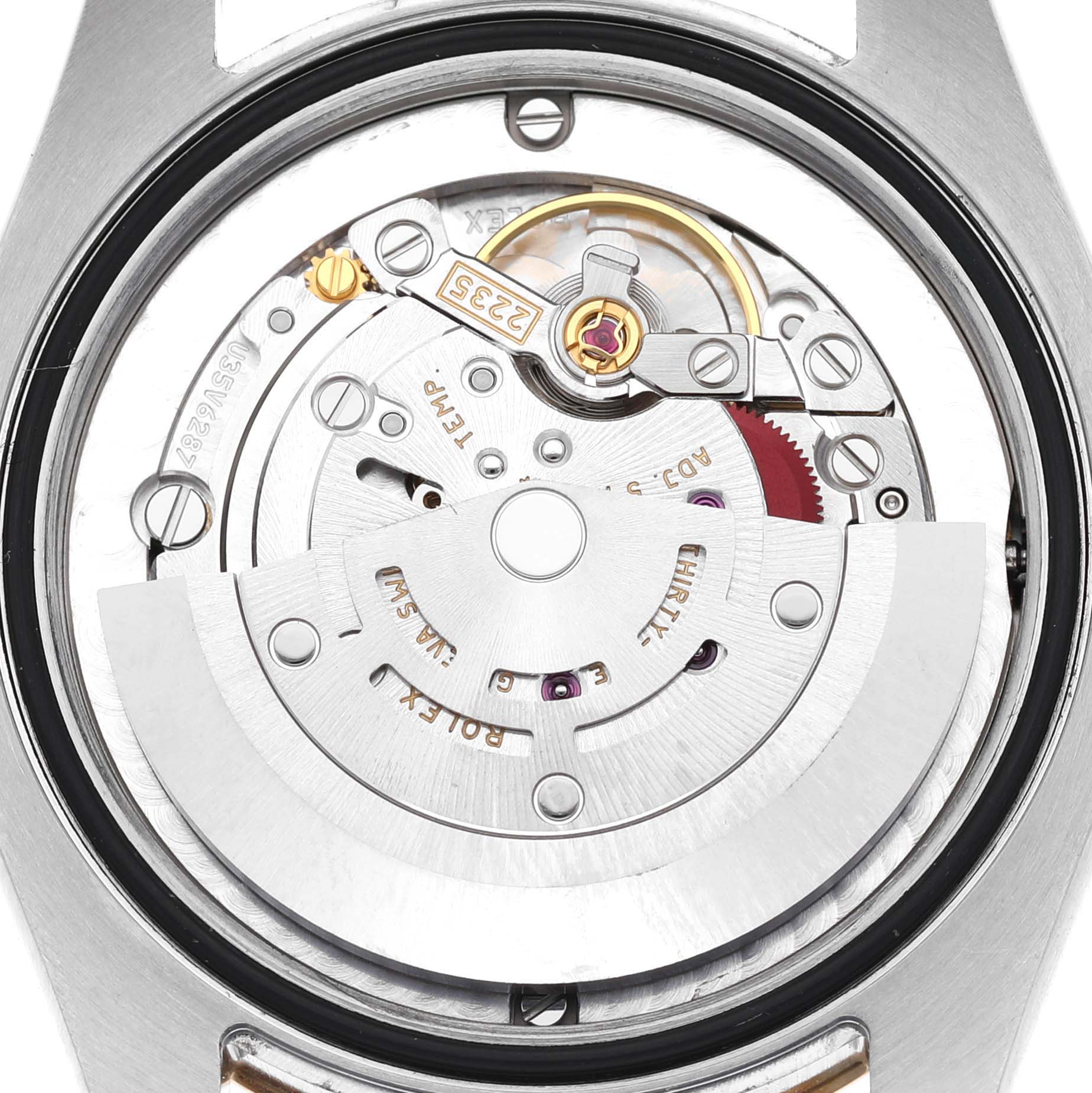 The image shows the movement mechanism of a Rolex Mid-Size 178273 Women's Steel and Gold (two tone) Black Dial model, viewed from the back, highlighting intricate gears and components.