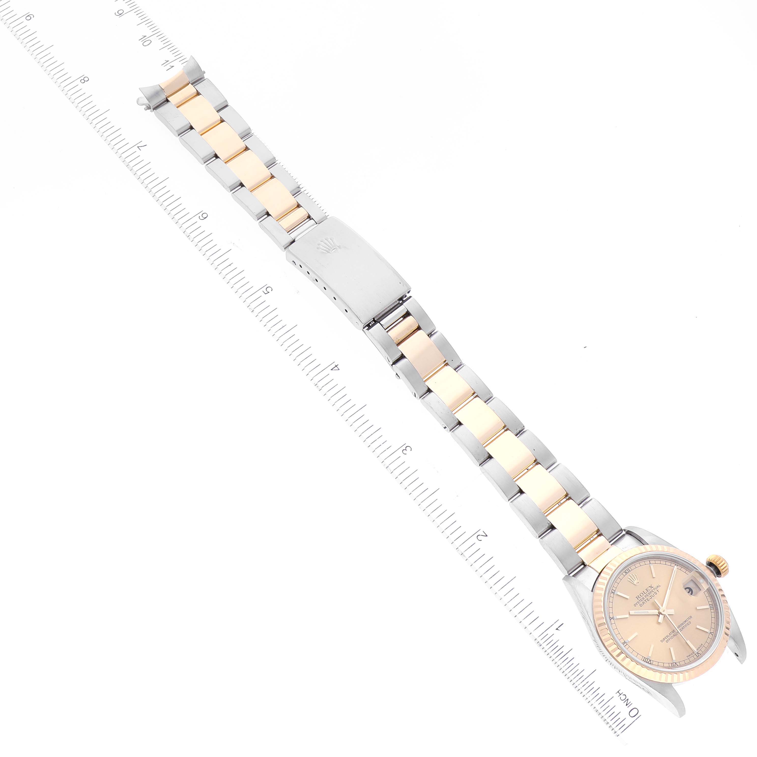 The image shows a Rolex Mid-Size 78273 Women
s Steel and Gold (two tone) Champagne Dial 78273 Women
s Steel and Gold (two tone) Champagne Dial model watch laid flat from the top, including the face and bracelet with a ruler for scale.
