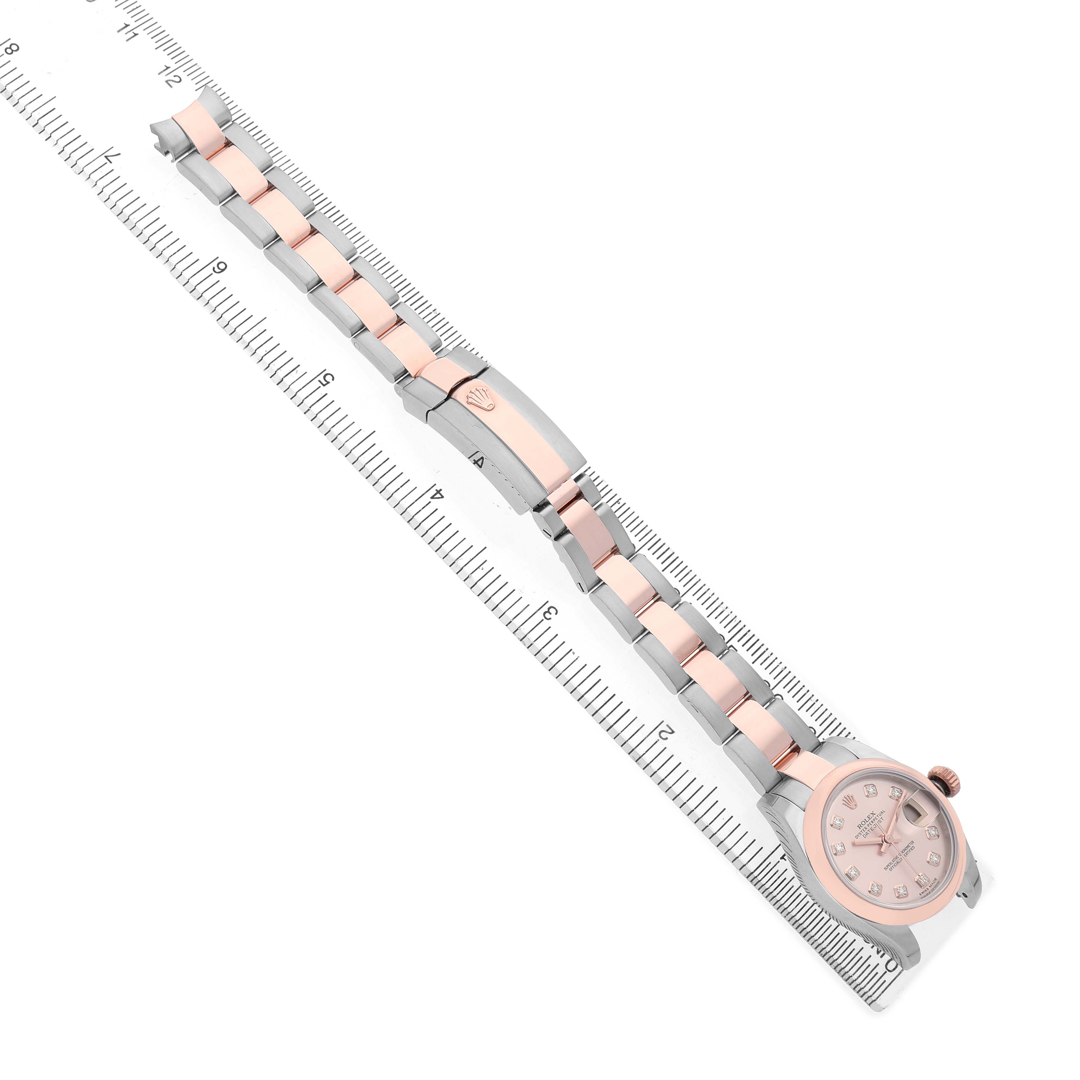 The Rolex Datejust 179161 Women's Steel and Gold (two tone) Pink Dial watch is shown from a top-down angle, highlighting its bracelet aligned with a ruler for measurement.