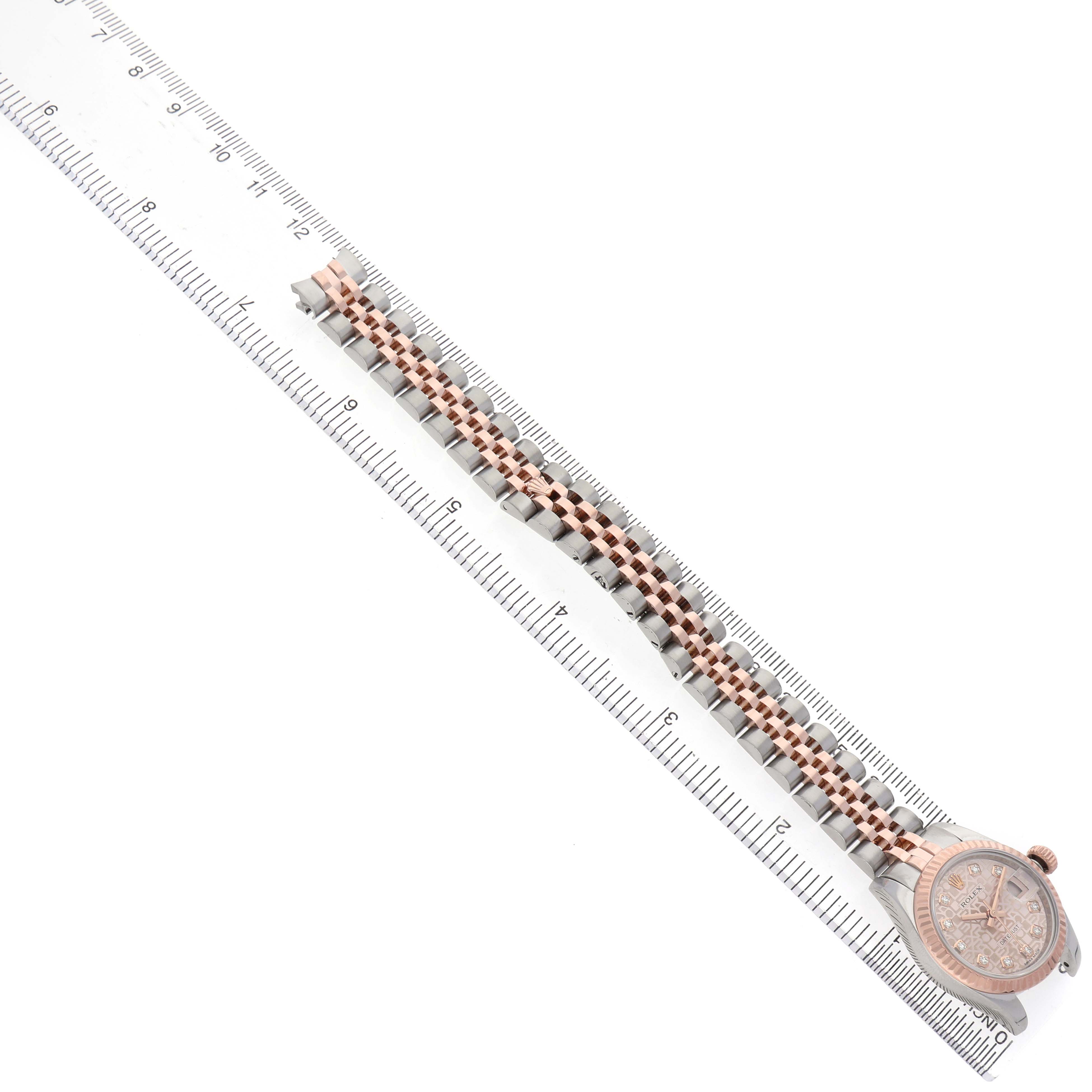 The Rolex Datejust 179171 Women's Steel and Gold (two tone) Pink Dial watch is shown from the top, displaying the bracelet and the face next to a ruler.