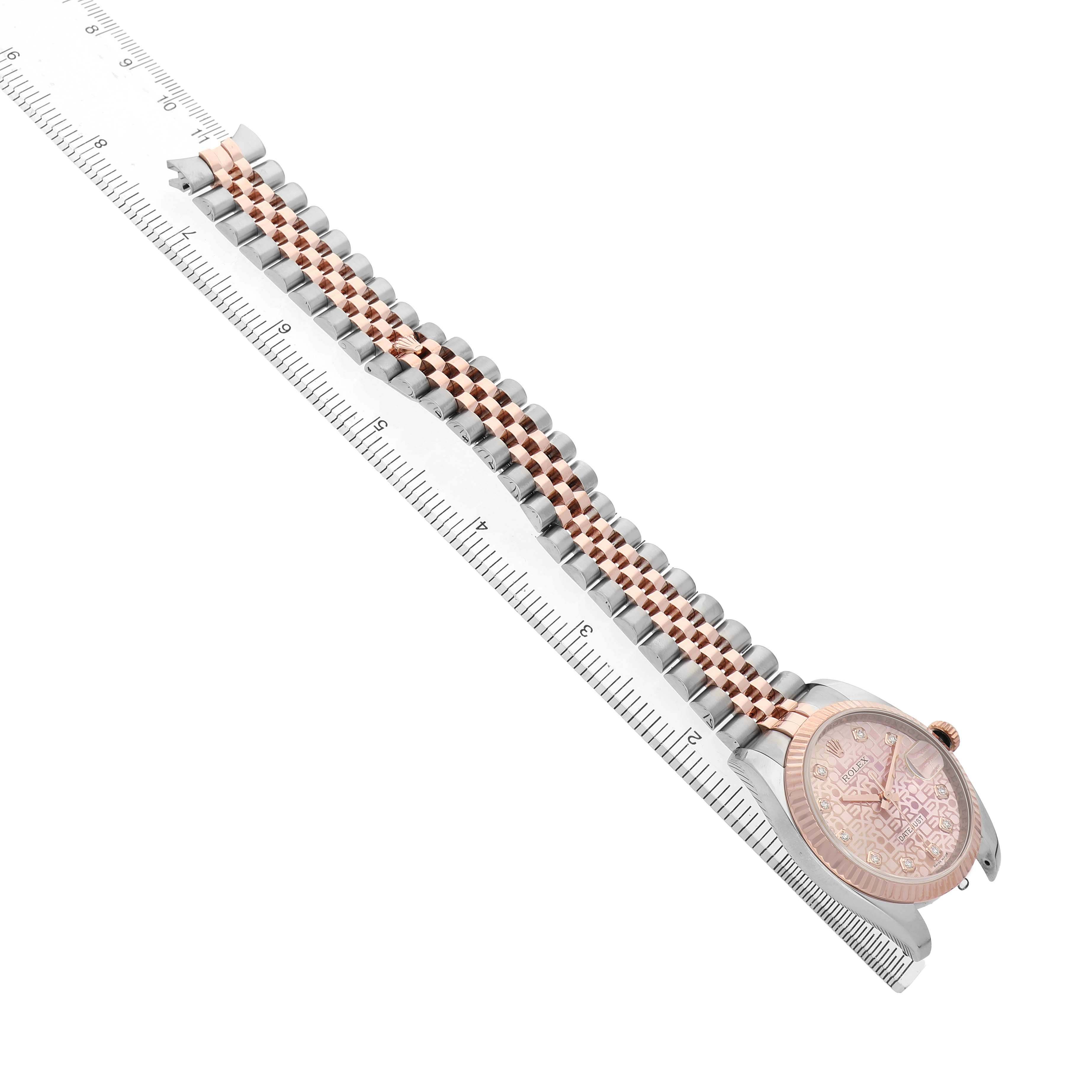The Rolex Datejust 116231 Men's Steel and Gold (two tone) Pink Dial watch is shown from a top angle, displaying its face, bezel, and bracelet alongside a ruler.