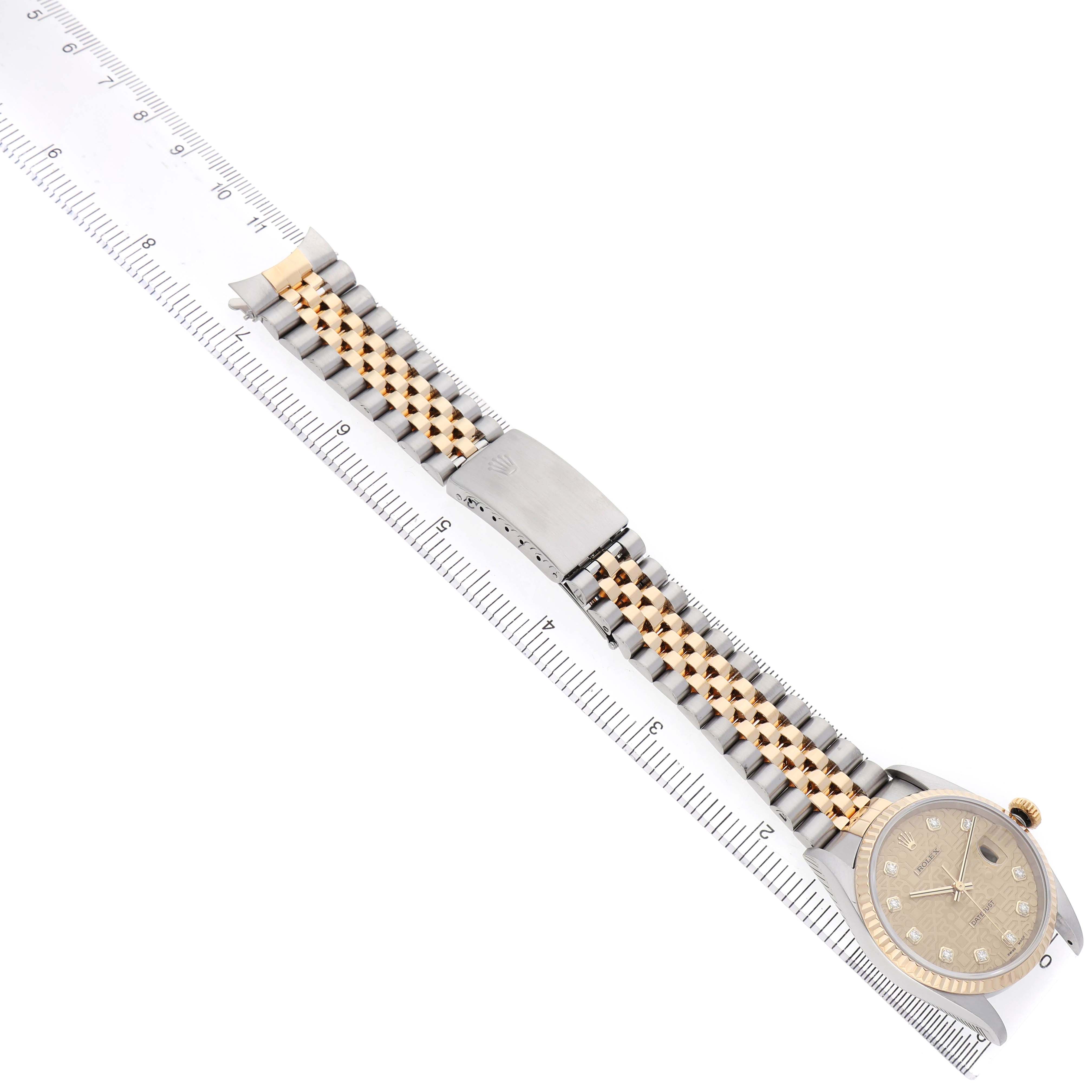 The Rolex Datejust 16233 Men's Stainless Steel Champagne Dial watch is shown from a top view, displaying the face, bracelet, and clasp next to a ruler.