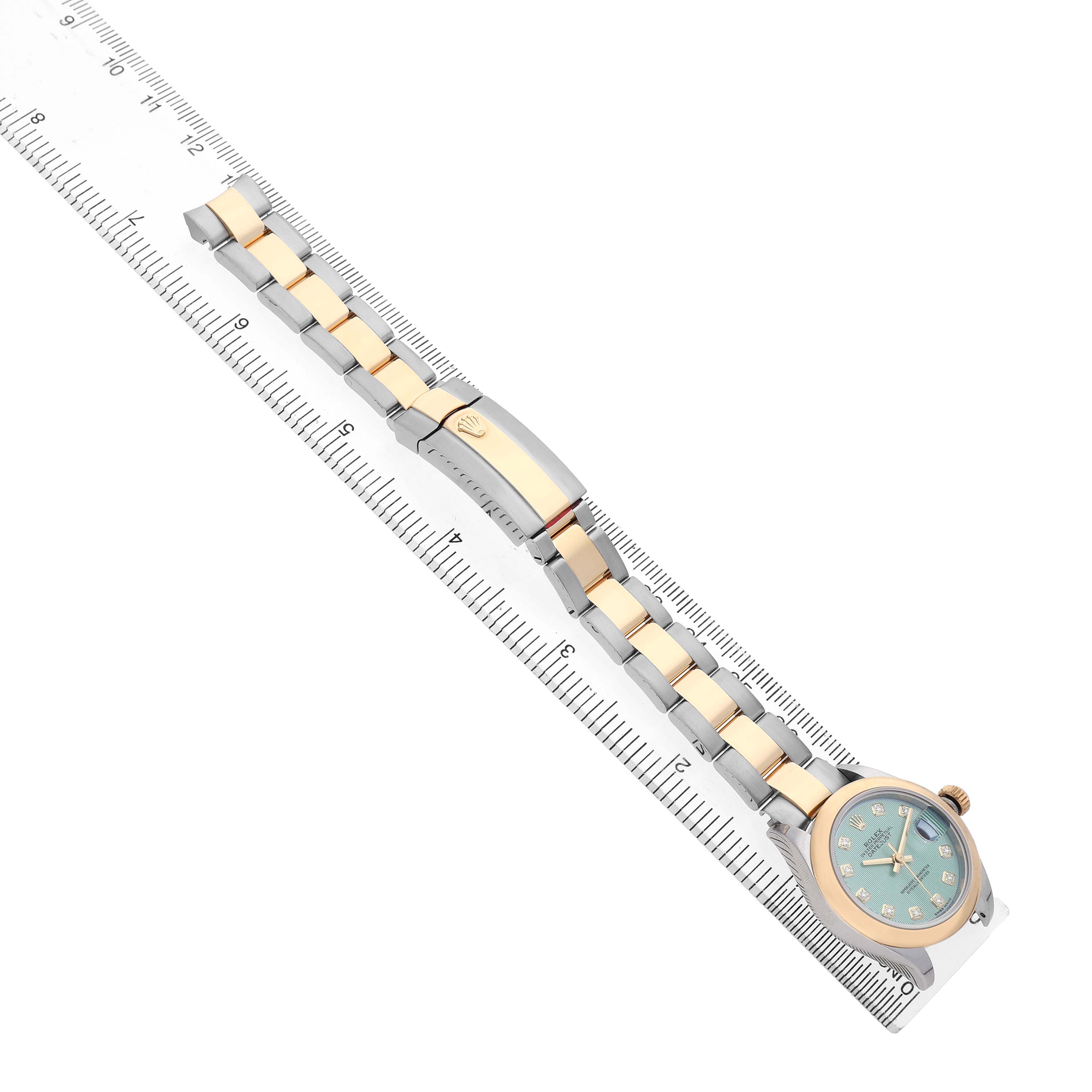 The Rolex Datejust 279163 Women's Steel and Gold (two tone) Green Dial watch is displayed diagonally, showing the face, bezel, and full metal bracelet with a ruler for scale.