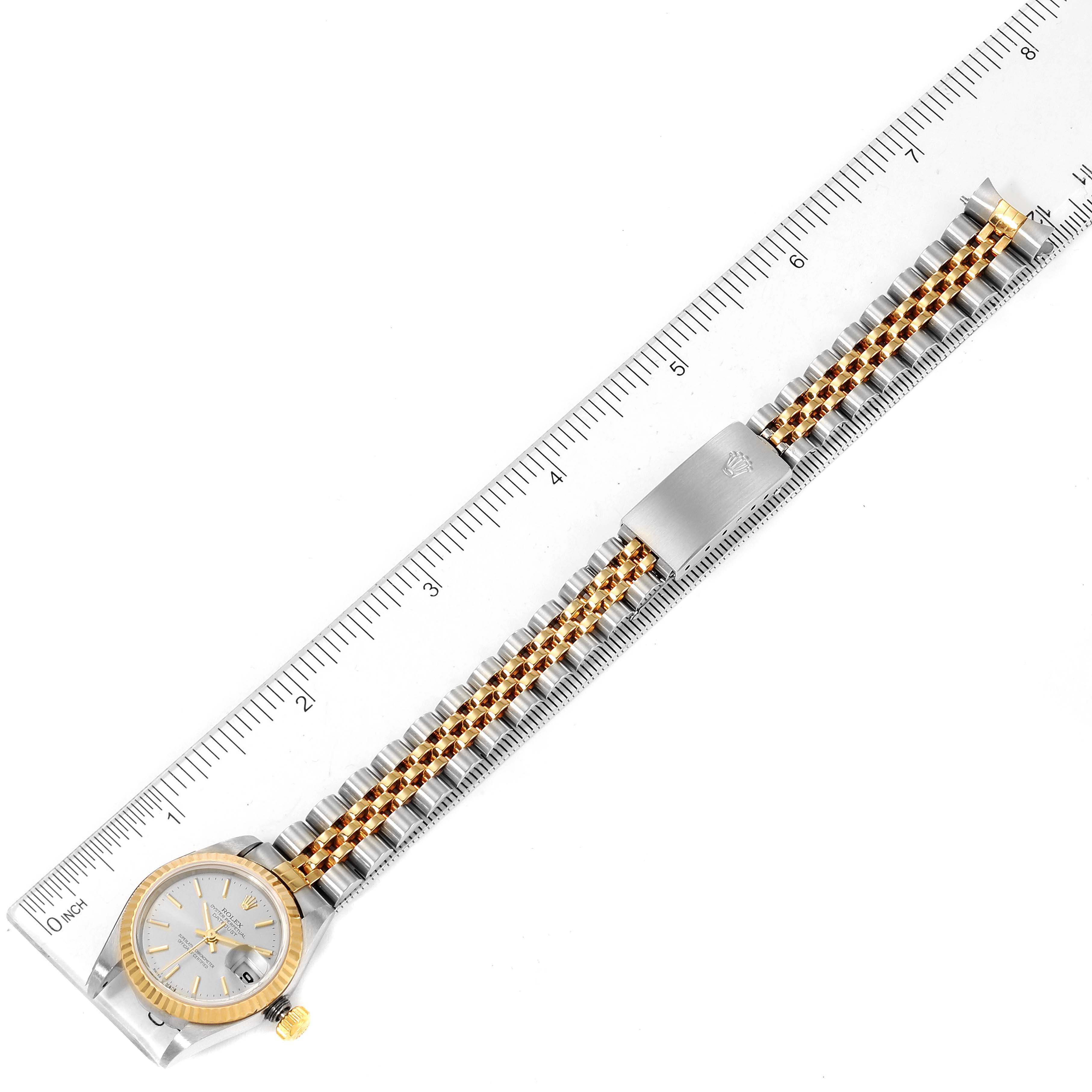 This image shows a Rolex Datejust 79173 Women
s Steel and Gold (two tone) Silver Dial 79173 Women
s Steel and Gold (two tone) Silver Dial watch laid flat with a ruler for size reference, highlighting the watch face, bezel, and bracelet.