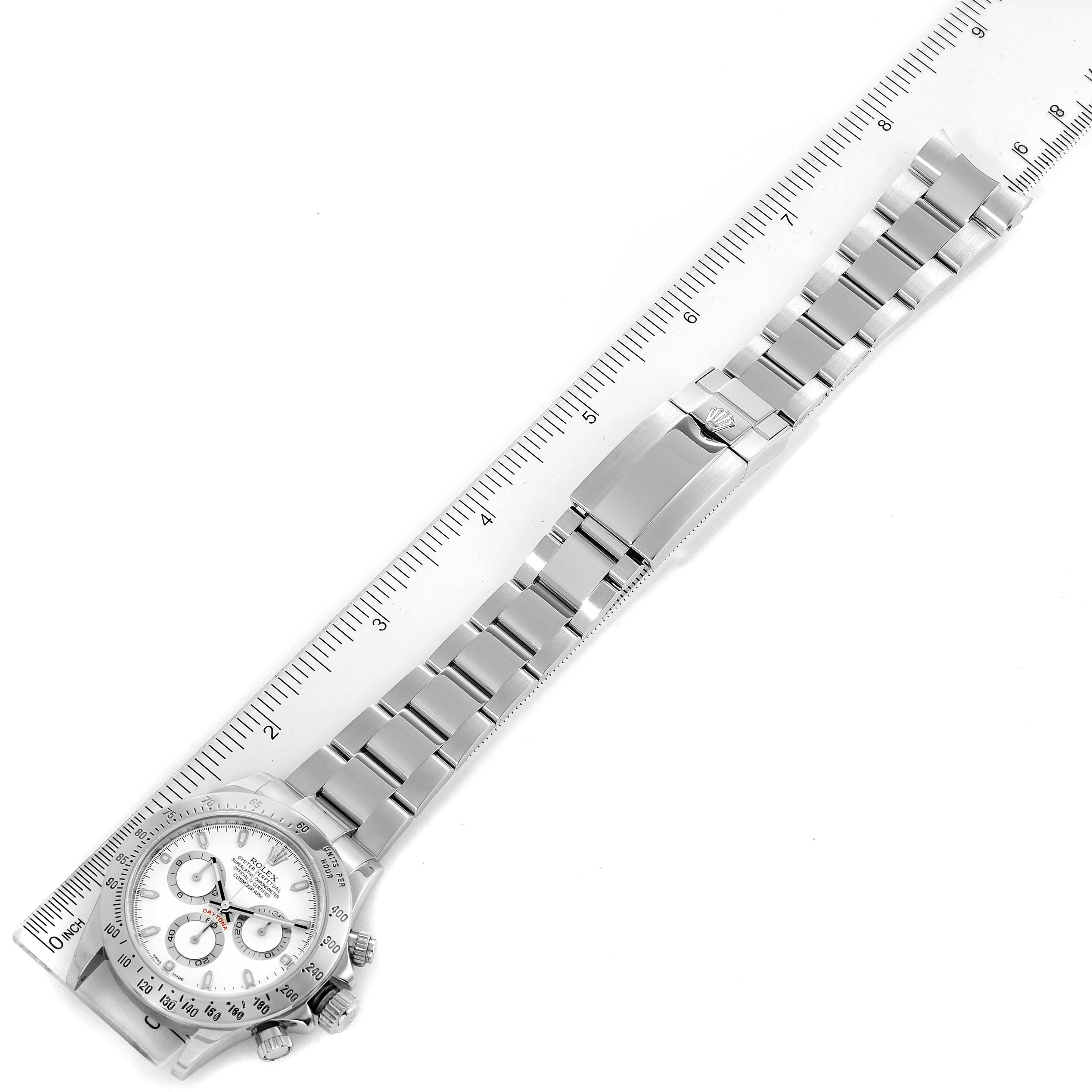 The image shows a top-down view of the entire Rolex Daytona 116520 Men
s Stainless Steel White Dial 116520 Men
s Stainless Steel White Dial watch along with a ruler for scale.