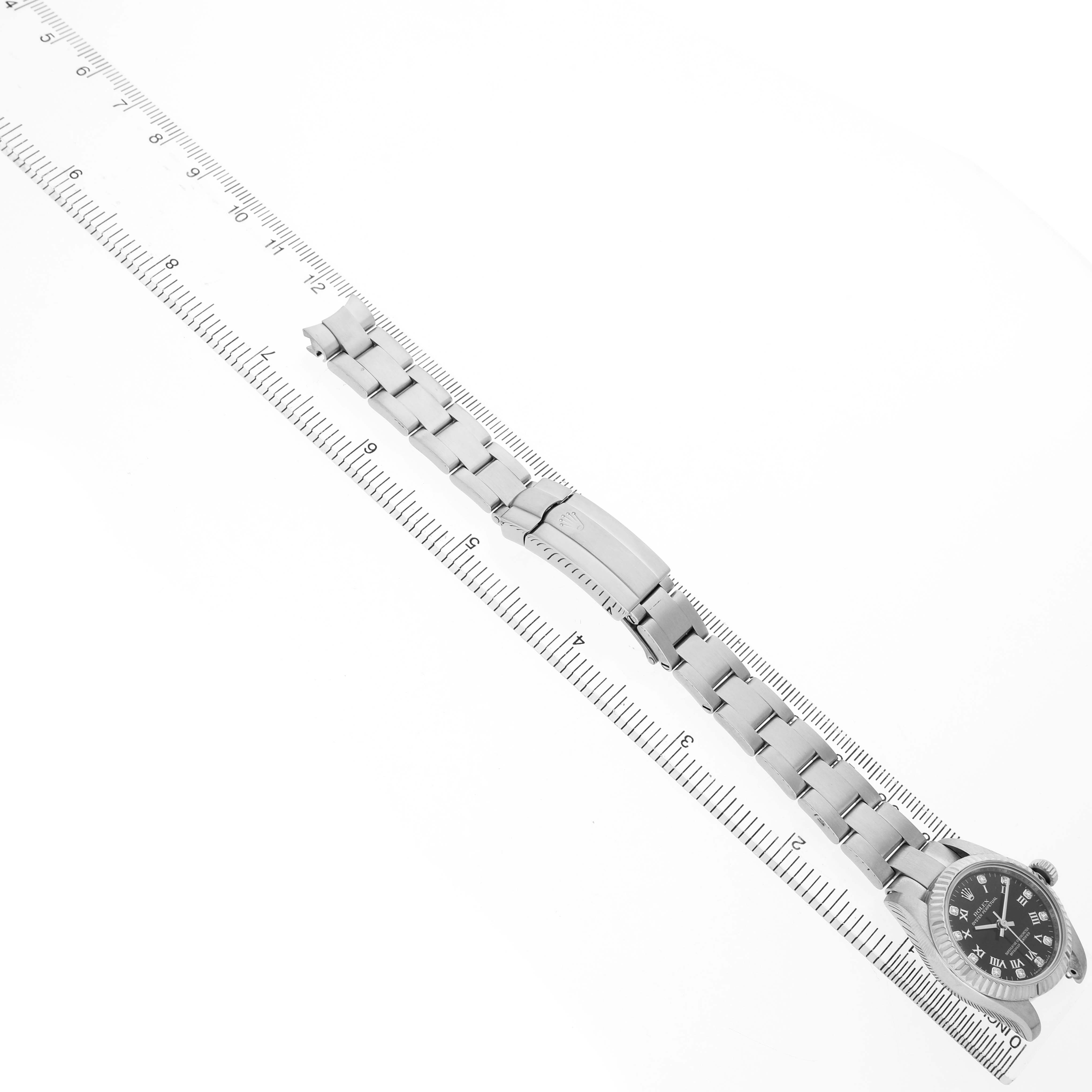 The Rolex Oyster Perpetual 176234 Women's Stainless Steel Black Dial watch is shown at an angle, displaying the face and full bracelet against a ruler backdrop.