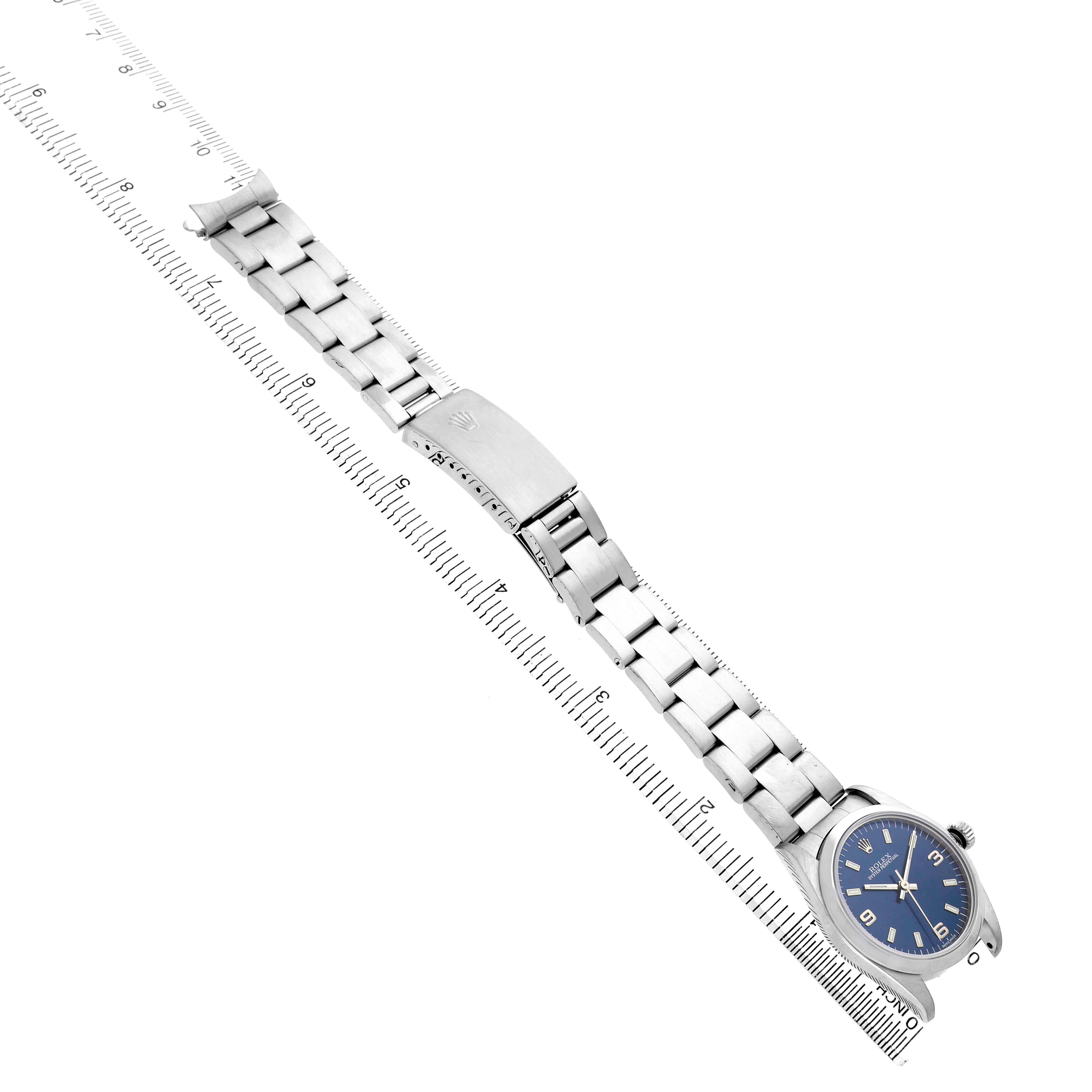 The image shows a Rolex Mid-Size 77080 Women's Stainless Steel Blue Dial watch flat with its face, bracelet, and clasp visible, alongside a ruler for scale.