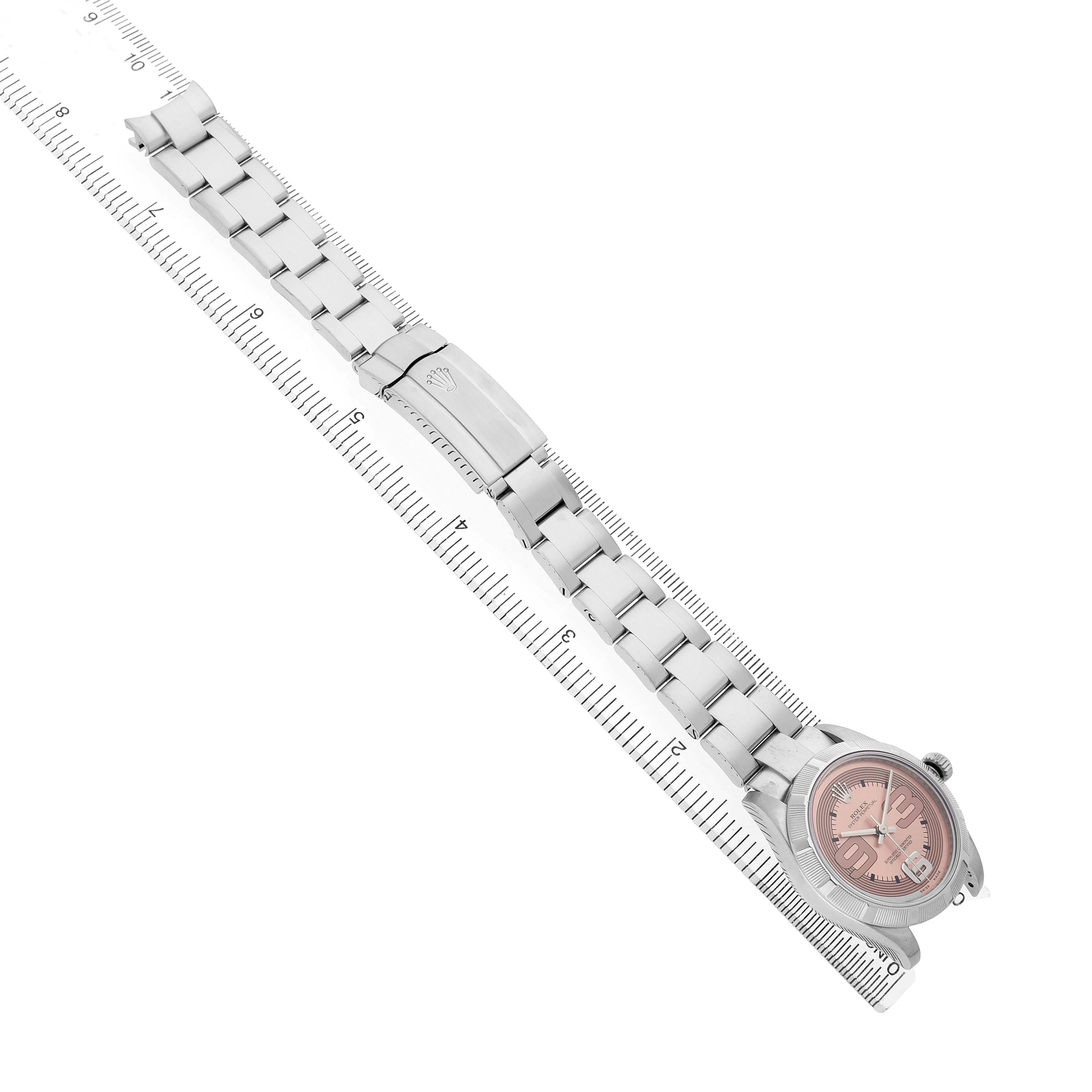 The Rolex Mid-Size 177210 Women's Stainless Steel Pink Dial watch is shown from above, displaying the pink dial, bracelet, and clasp beside a ruler.