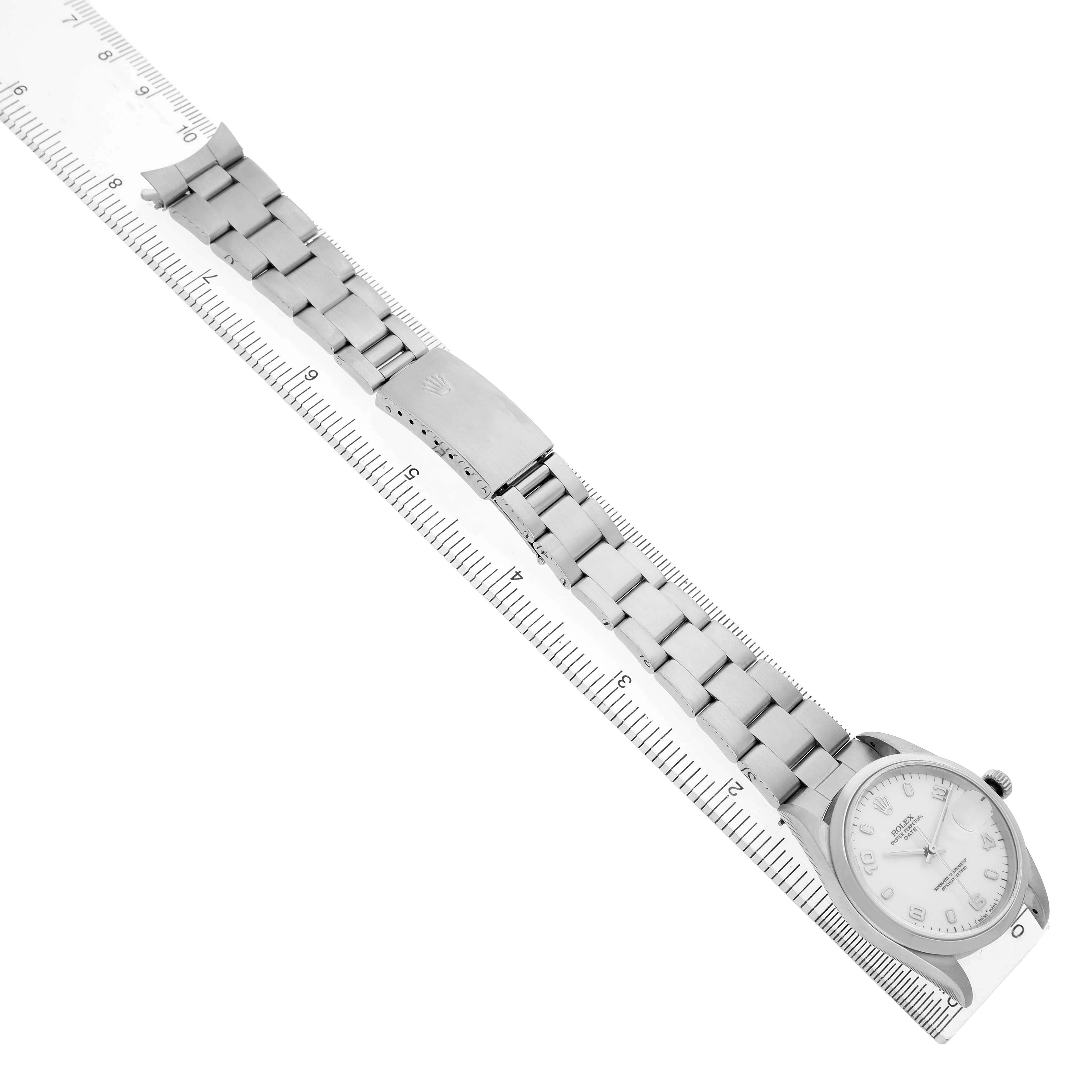 The Rolex Date 15200 Men's Stainless Steel White Dial watch is displayed at a slight angle, showcasing the full bracelet, clasp, and watch face beside a ruler for scale.