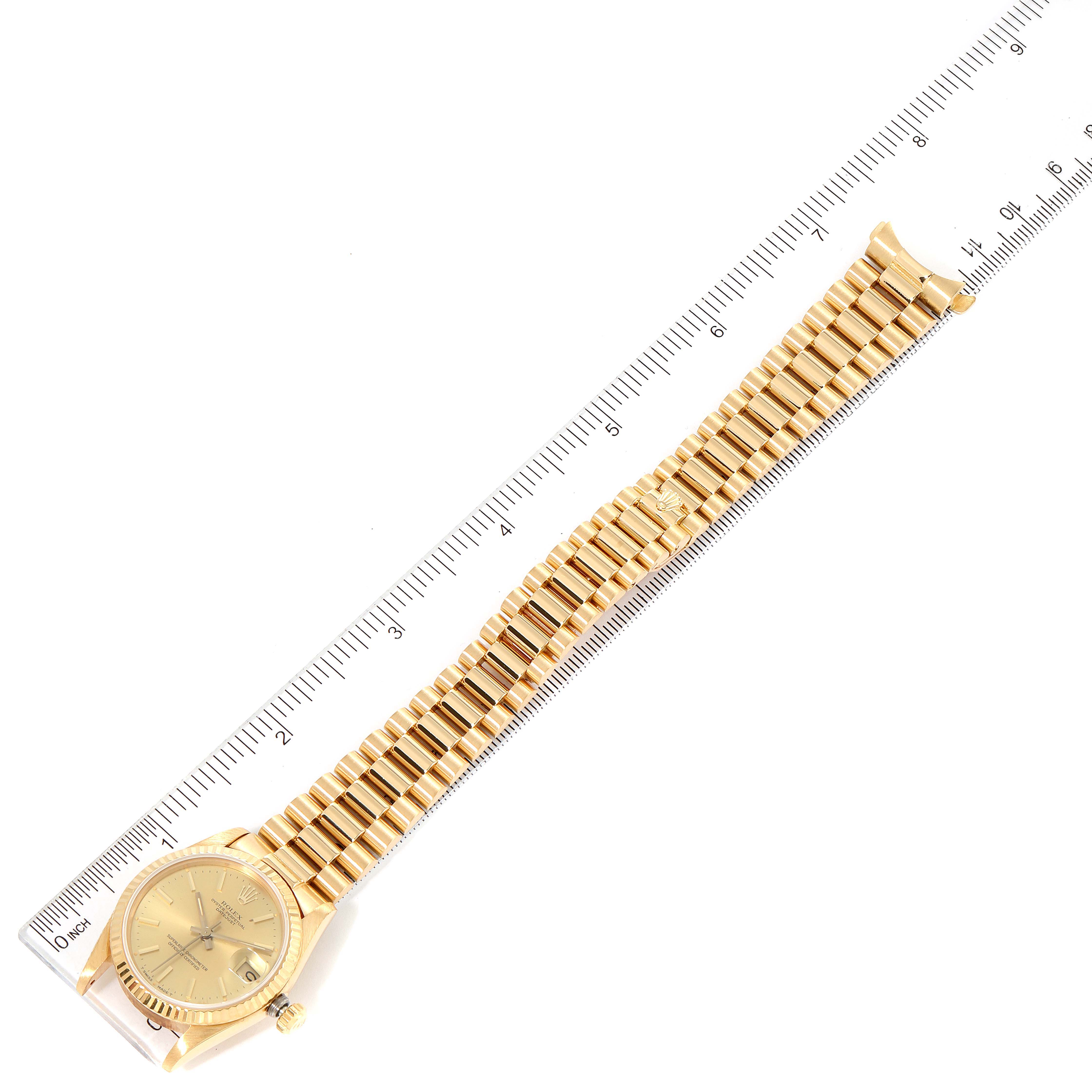 The image shows a Rolex President 68278 Women
s Yellow Gold Champagne Dial 68278 Women
s Yellow Gold Champagne Dial model watch positioned next to a ruler, displaying its gold bracelet and dial.