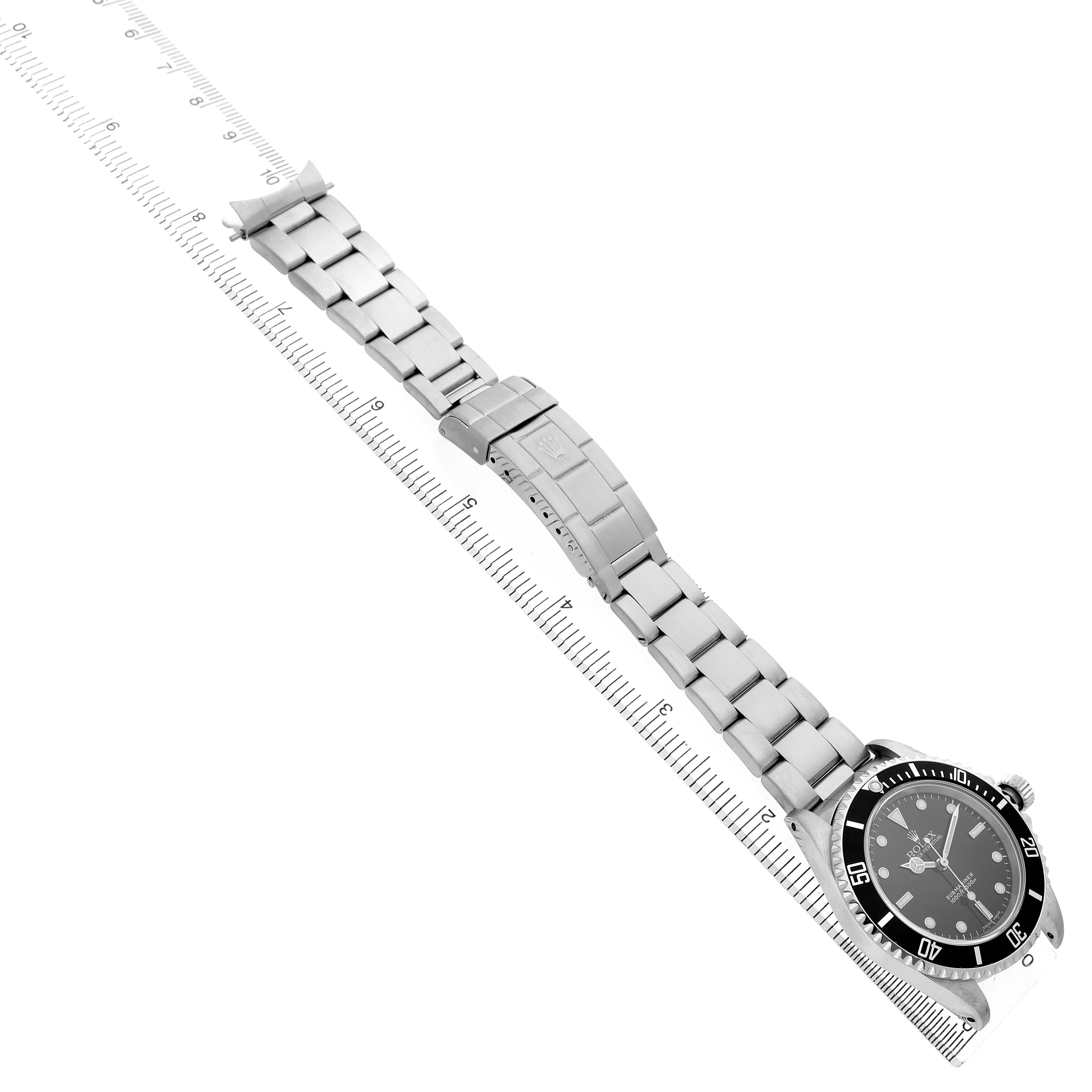 The image shows a Rolex Submariner 14060 Men's Stainless Steel Black Dial watch from an angled top view, highlighting the face, bezel, and metal bracelet aligned with a ruler.