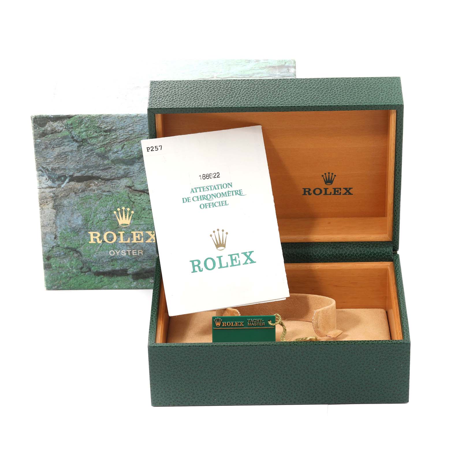 The image shows an open green Rolex box with its outer box, official certification booklet, and a tag for the Yacht-Master model.
