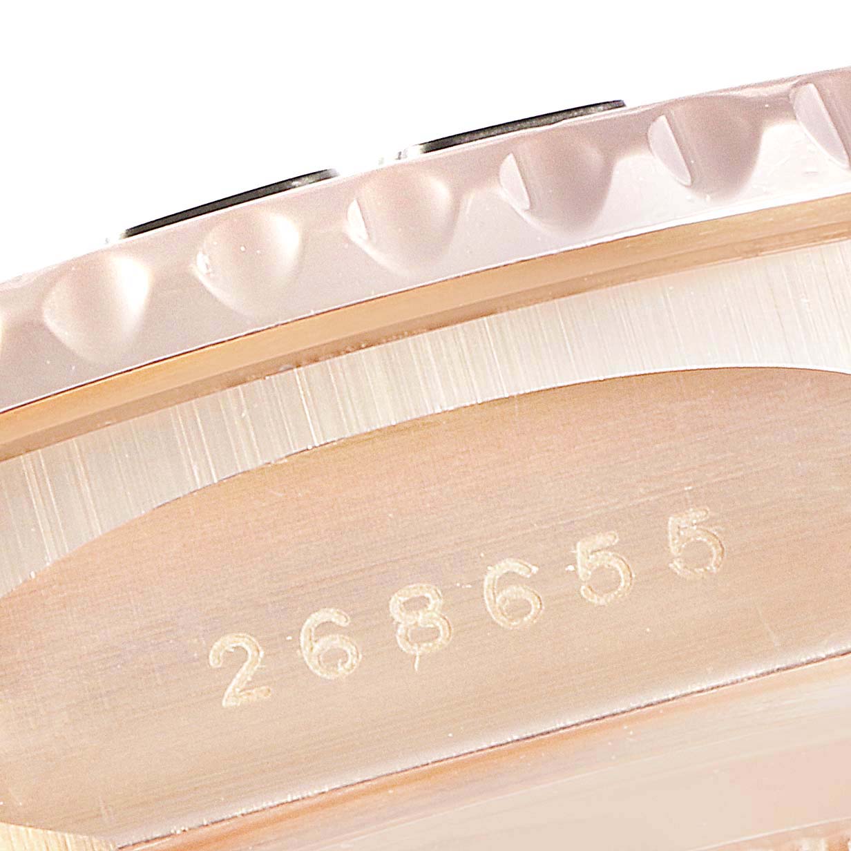 This close-up image of the Rolex Yacht-Master 268655 Men's Rose Gold Black Dial 268655 Men's Rose Gold Black Dial watch shows its bezel and a part of its case with a serial number engraved.