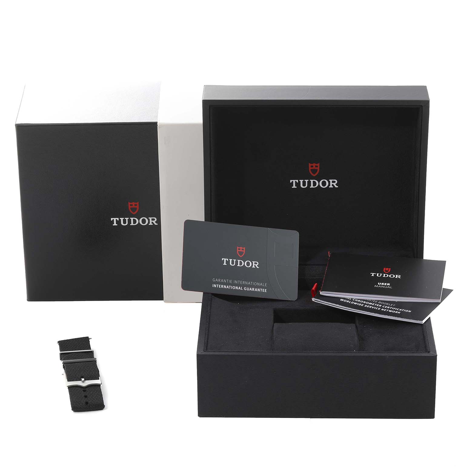 This image shows the packaging, international guarantee card, manuals, and a strap for a Tudor Heritage Black Bay 79230G Men's Stainless Steel Black Dial 79230G Men's Stainless Steel Black Dial watch.