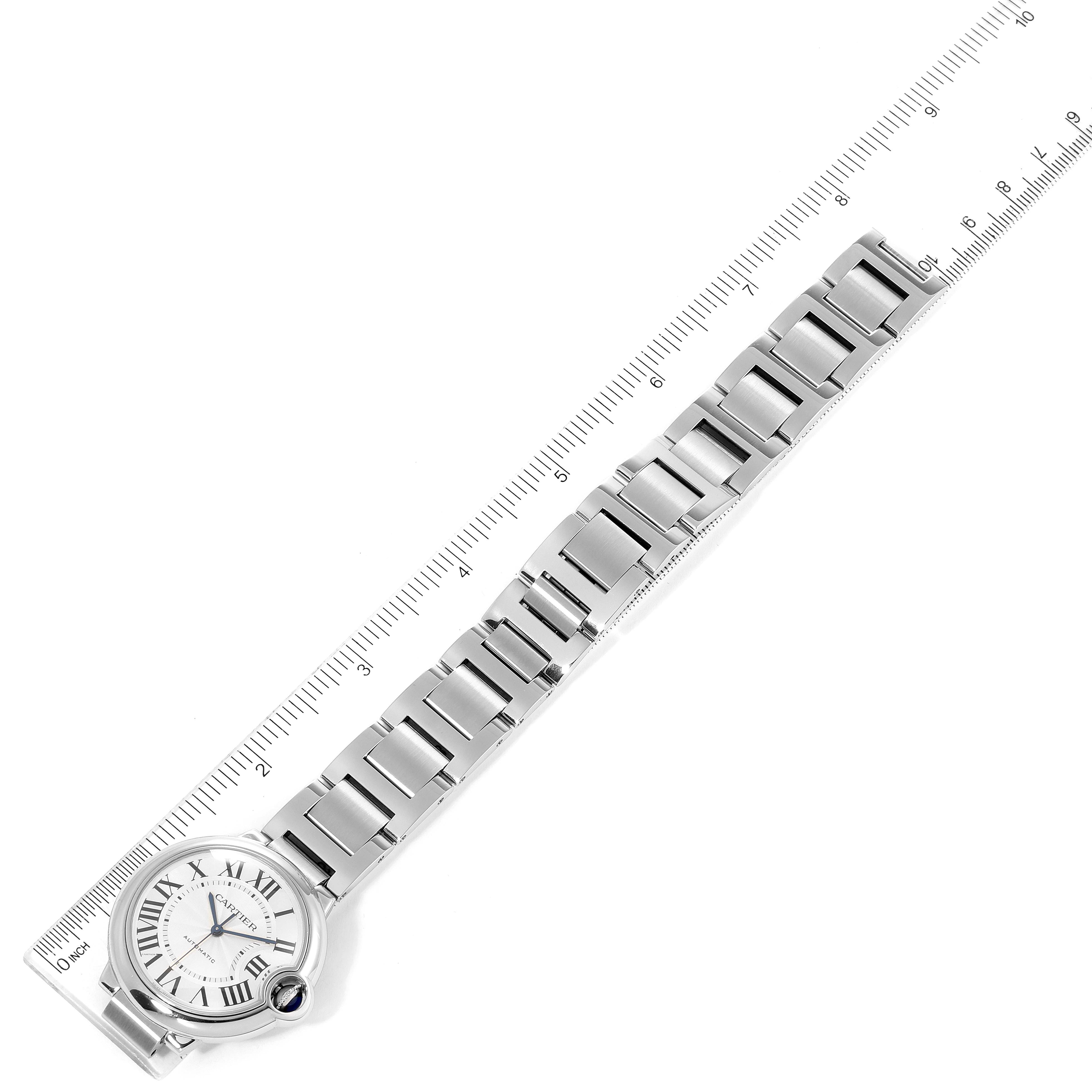 The image shows a top-down view of a Ballon Bleu watch by Cartier, displaying the watch face, bracelet, and an attached ruler.