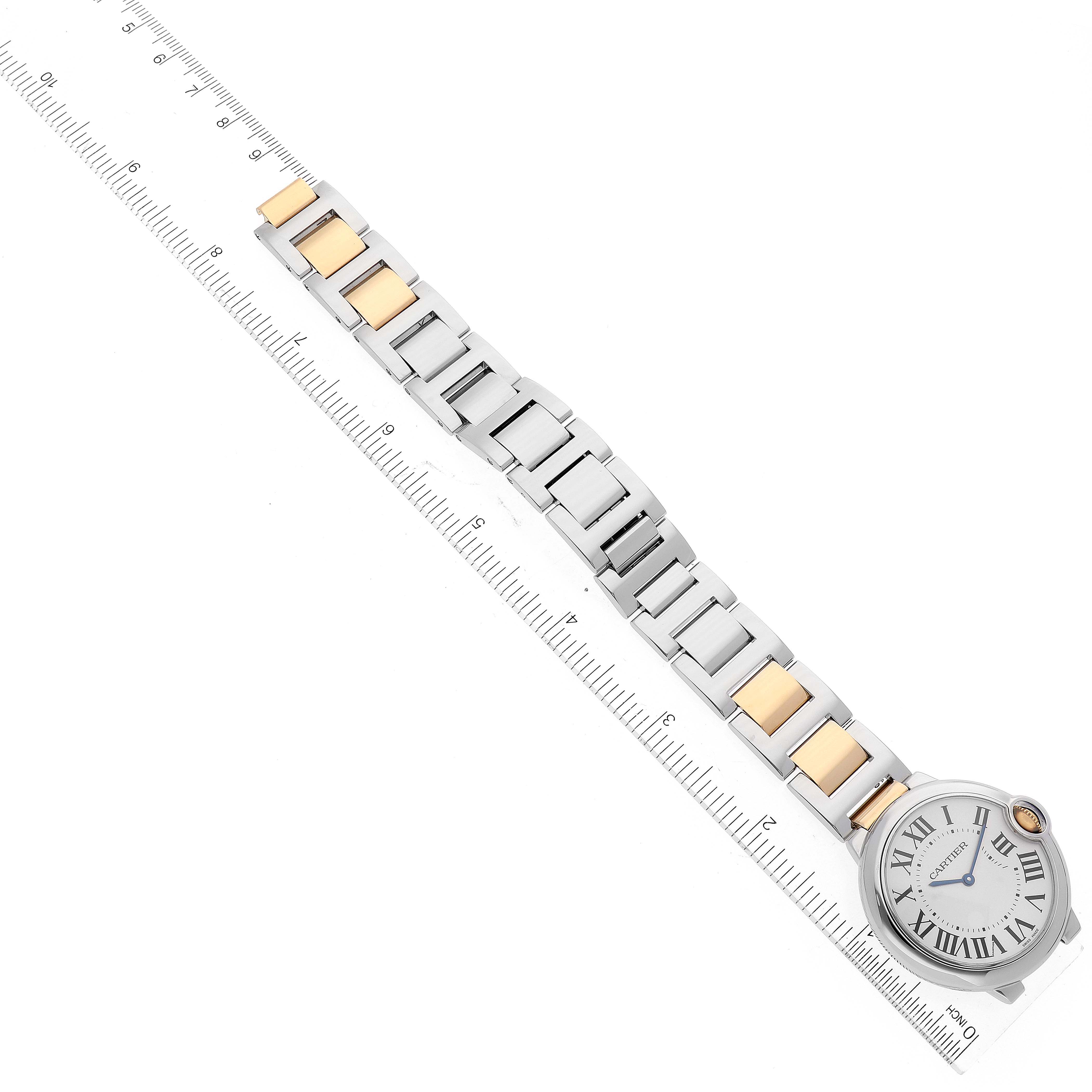 The image shows the Ballon Bleu by Cartier watch from an overhead angle, highlighting the band and face next to a ruler for size reference.