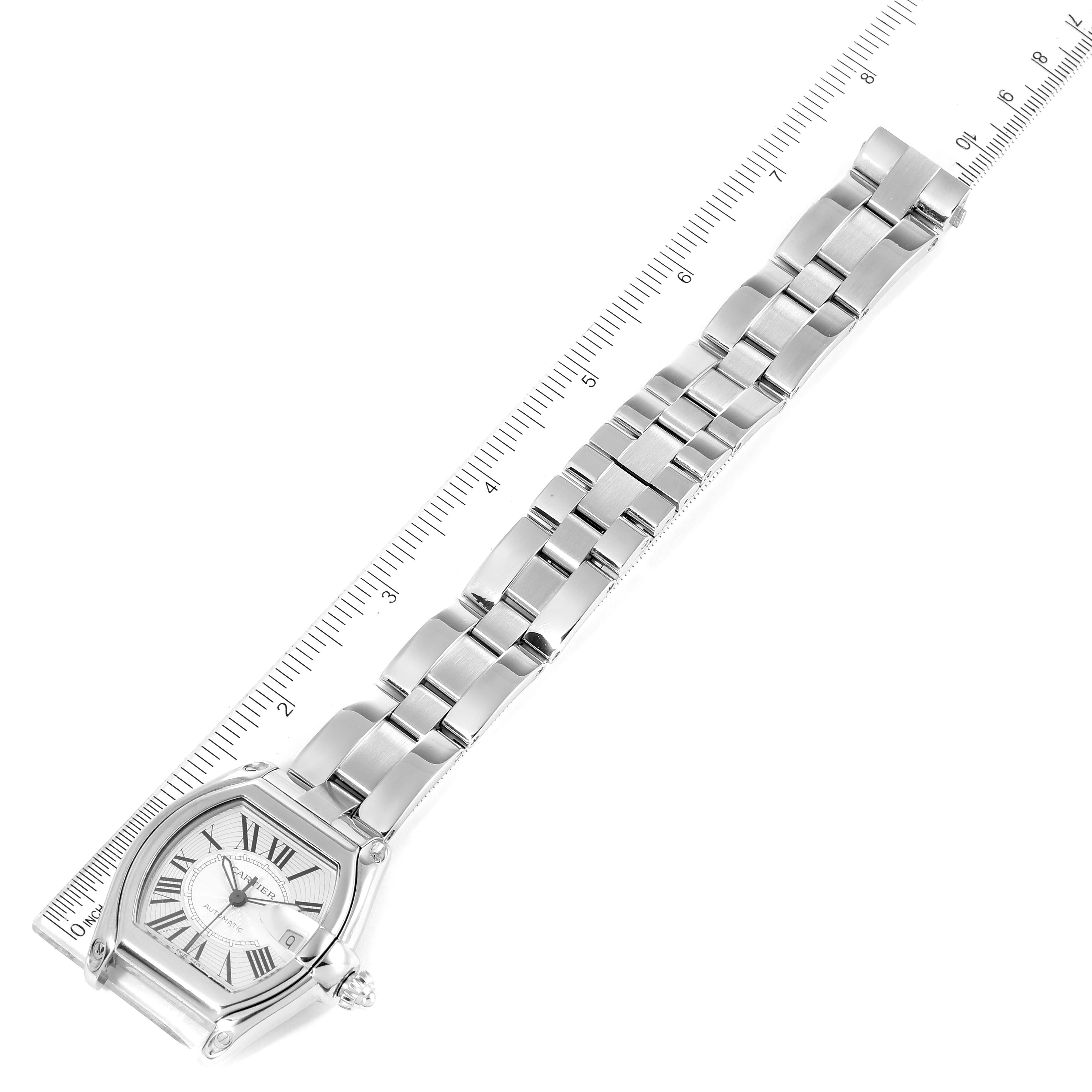 This image shows a top view of a Cartier Roadster W62025V3 Men
s Stainless Steel Silver Dial W62025V3 Men
s Stainless Steel Silver Dial watch, showcasing its full stainless steel band and face beside a ruler.