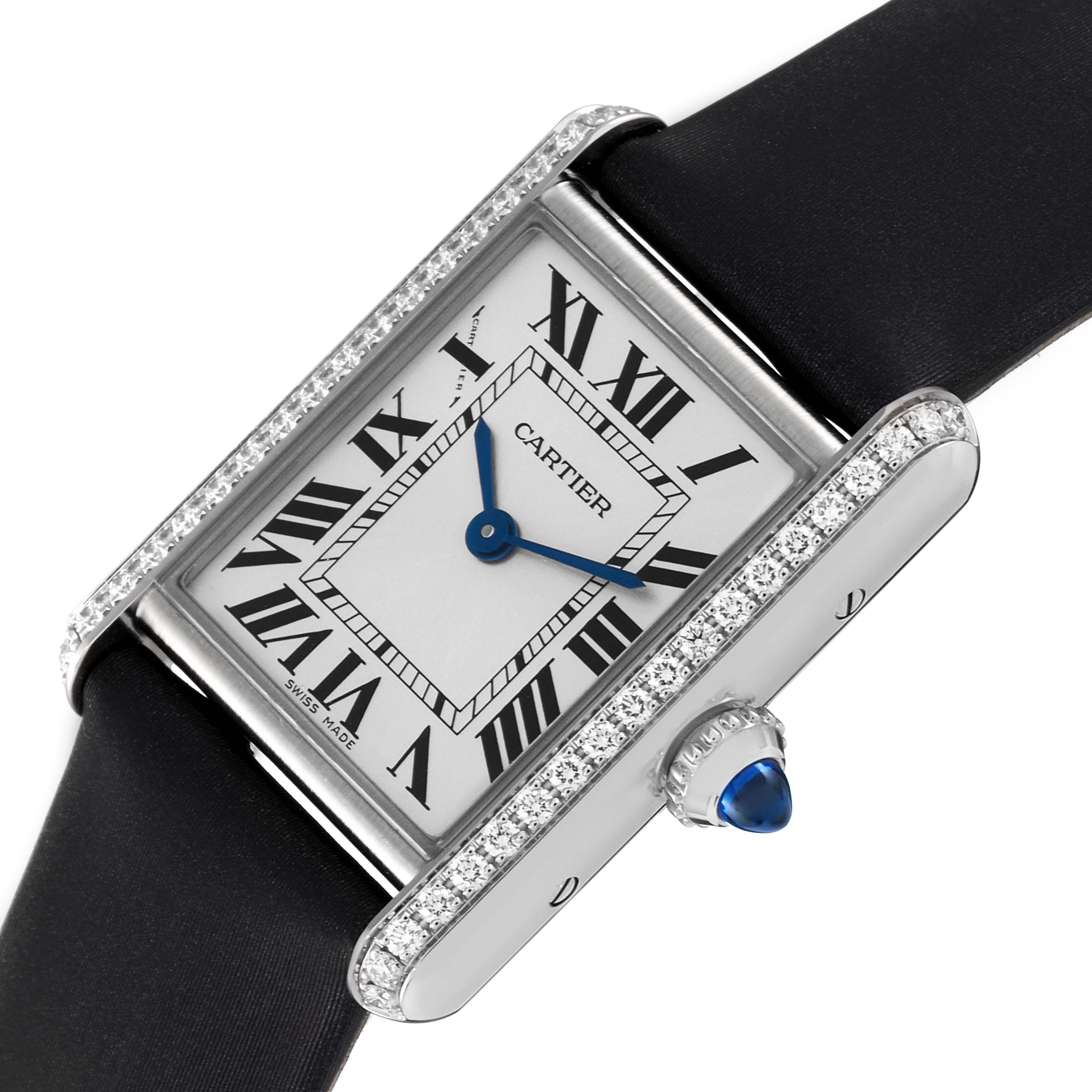 The image shows the Cartier Tank Must W4TA0016 Women's Stainless Steel Silver Dial W4TA0016 Women's Stainless Steel Silver Dial watch at an angle, highlighting its face, bezel with diamonds, strap, and blue cabochon crown.