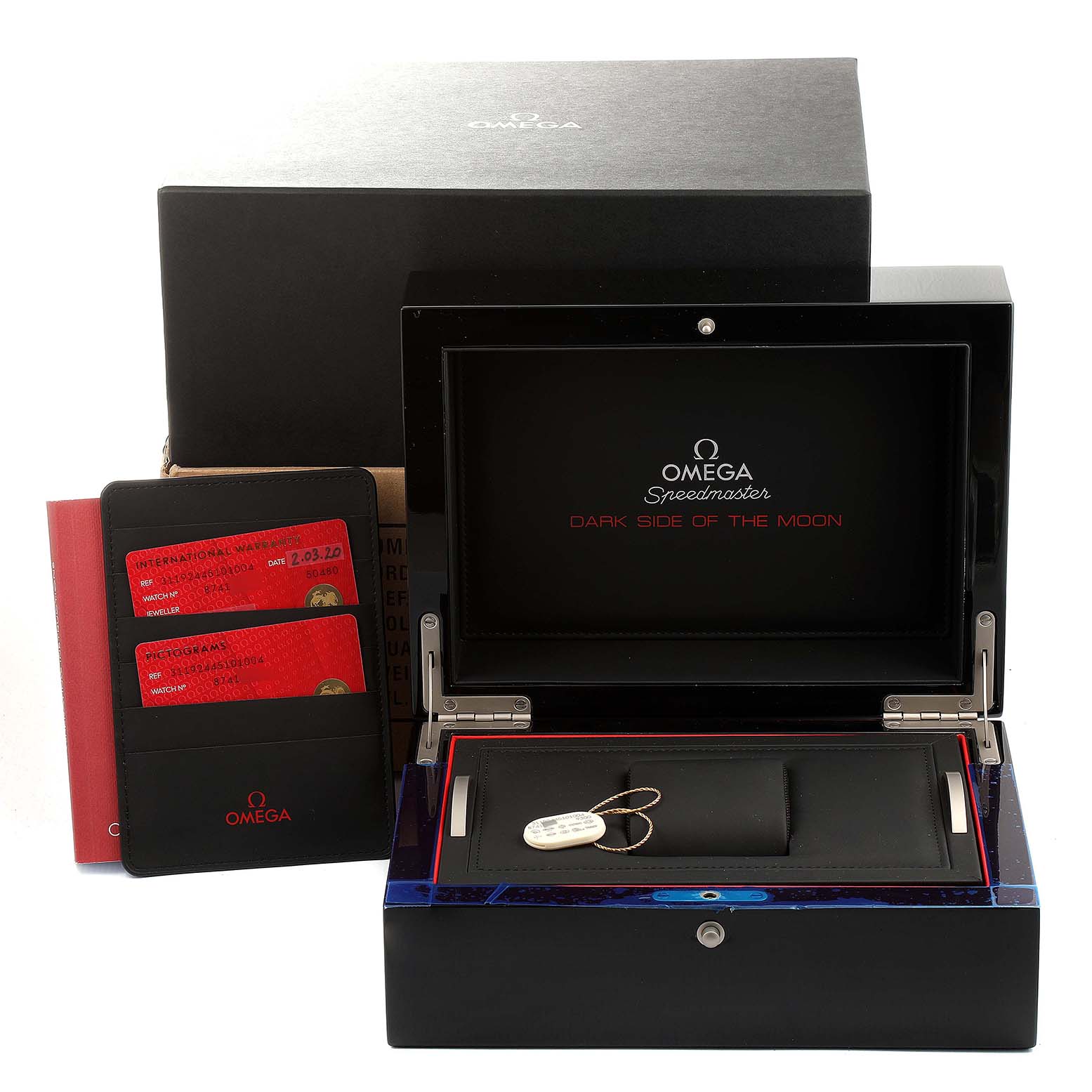 The image shows an Omega Speedmaster 311.92.44.51.01.004 Men's Ceramic Black Dial 311.92.44.51.01.004 Men's Ceramic Black Dial "Dark Side of the Moon" box with documentation and accessories from a front angle.