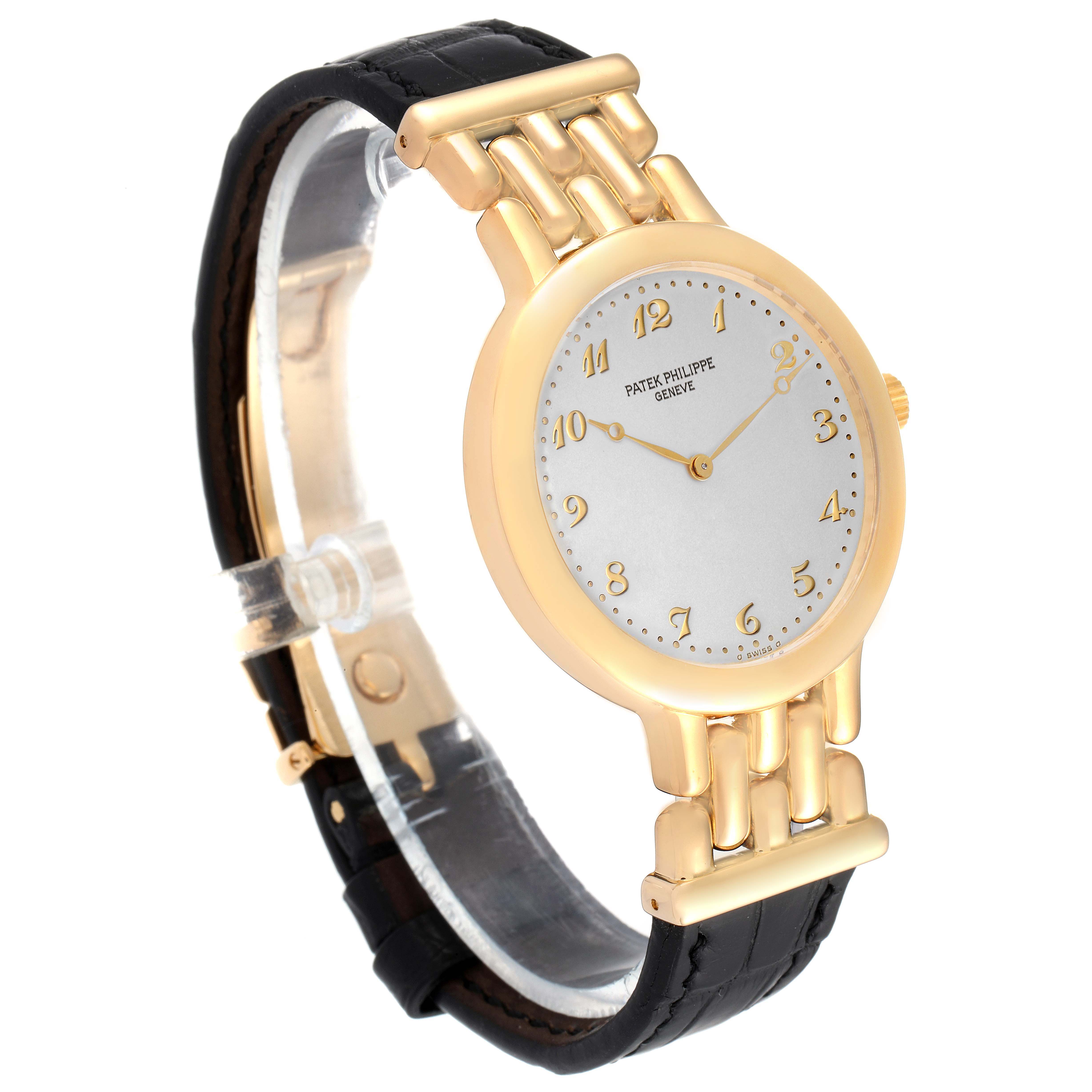 The image shows a side and front angled view of a Patek Philippe Calatrava 3915J Men's Yellow Gold Silver Dial 3915J Men's Yellow Gold Silver Dial watch with a gold case and a black leather strap.