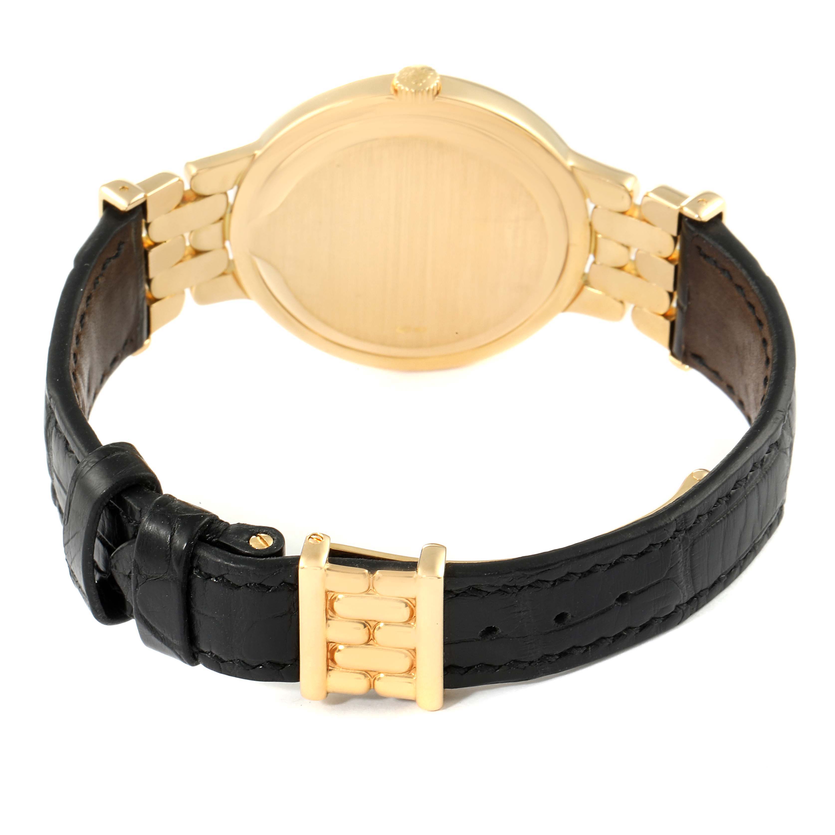 The image shows the back and strap of a Patek Philippe Calatrava 3915J Men's Yellow Gold Silver Dial 3915J Men's Yellow Gold Silver Dial watch with a gold case and black leather band.