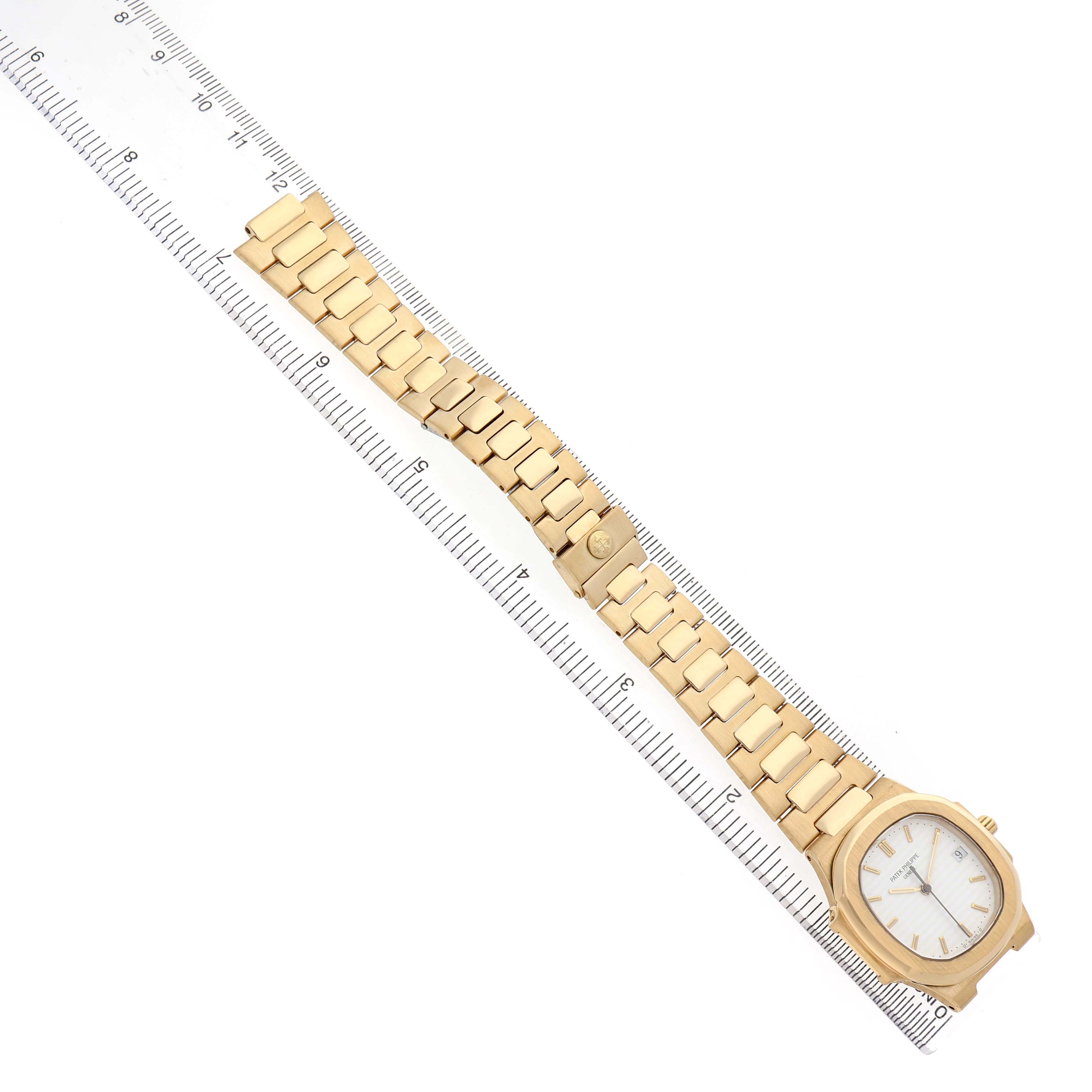 The image shows the Patek Philippe Nautilus 3900/1 Women's Yellow Gold White Dial watch from an overhead angle, highlighting the bracelet and face next to a ruler.