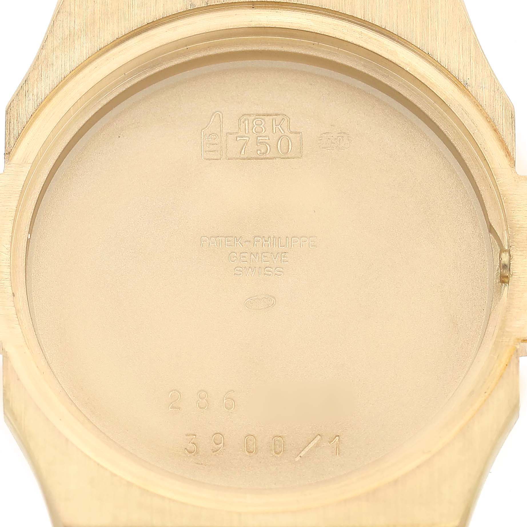 The image shows the inside of the case back for the Patek Philippe Nautilus 3900/1 Women's Yellow Gold White Dial, revealing engravings and gold markings.