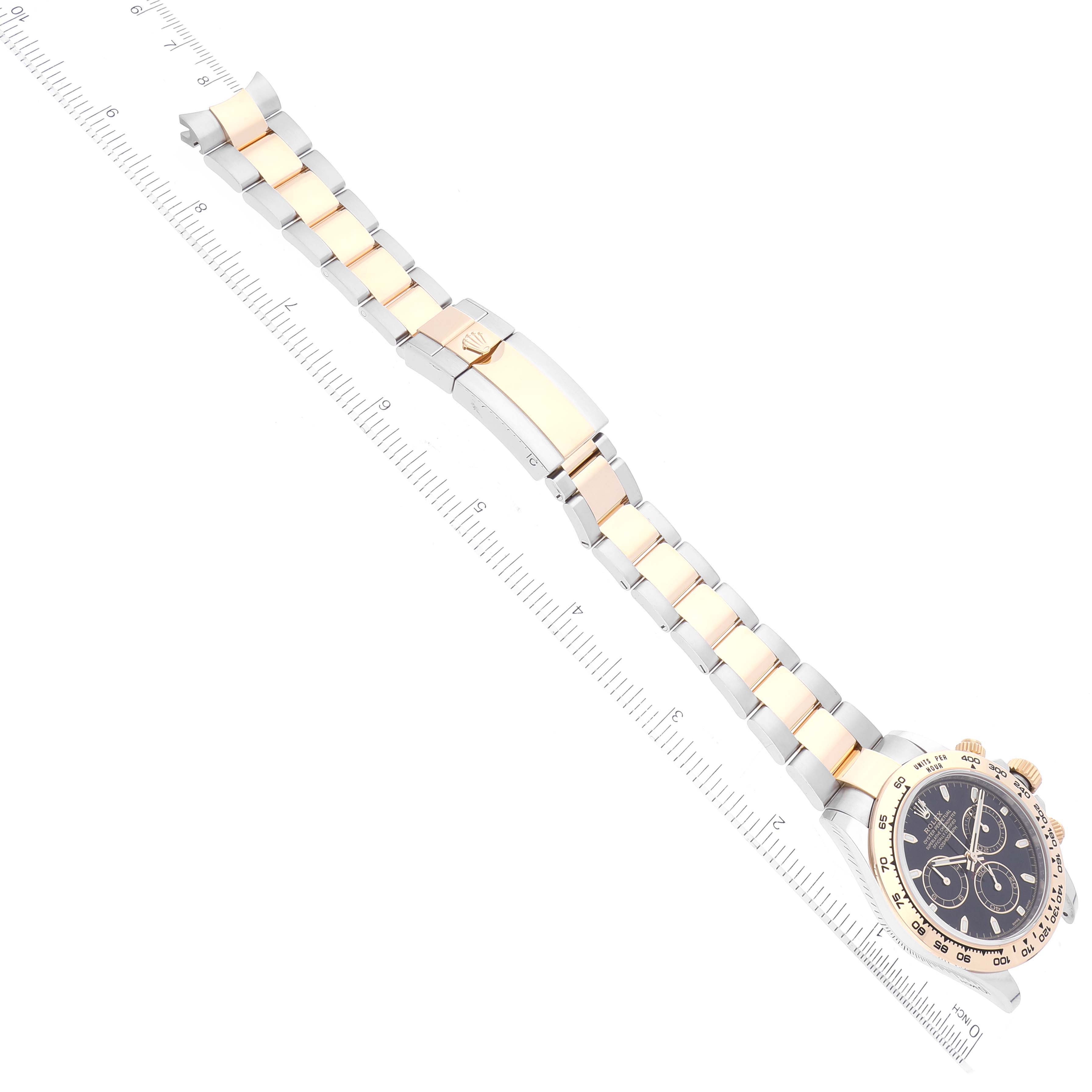 The image shows a Rolex Daytona 116503 Men
s Steel and Gold (two tone) Black Dial 116503 Men
s Steel and Gold (two tone) Black Dial watch laid flat with its face and full bracelet, plus a ruler for scale.
