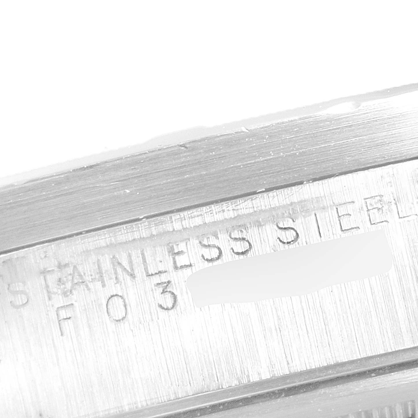This macro shot of a Rolex Date 15210 Men's Stainless Steel Black Dial 15210 Men's Stainless Steel Black Dial model displays a close-up of the engraved stainless steel text on the case.