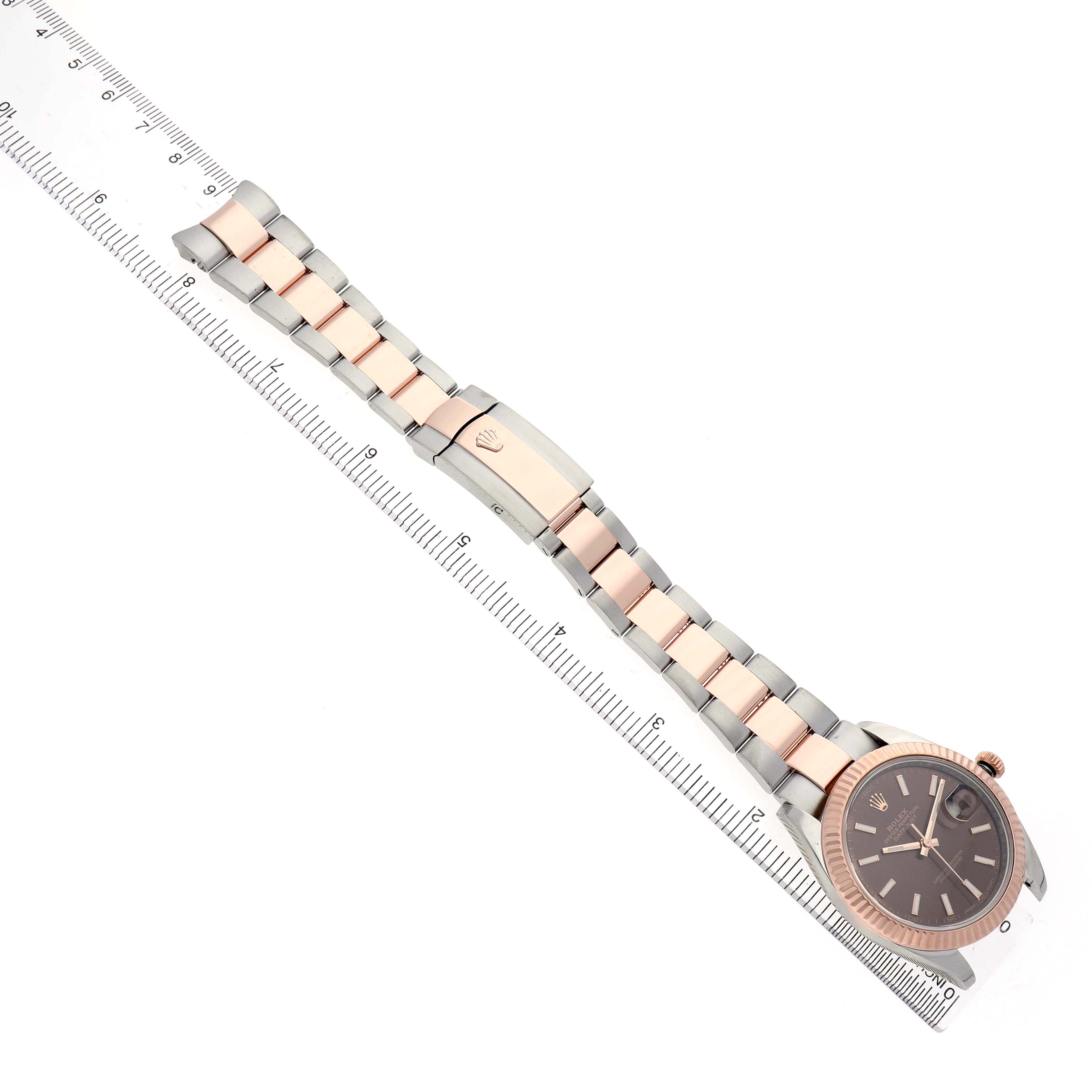 The Rolex Datejust 41 126331 Men's Steel and Gold (two tone) Brown Dial watch is shown at an angle displaying the dial, bezel, bracelet, and clasp alongside a ruler for size reference.