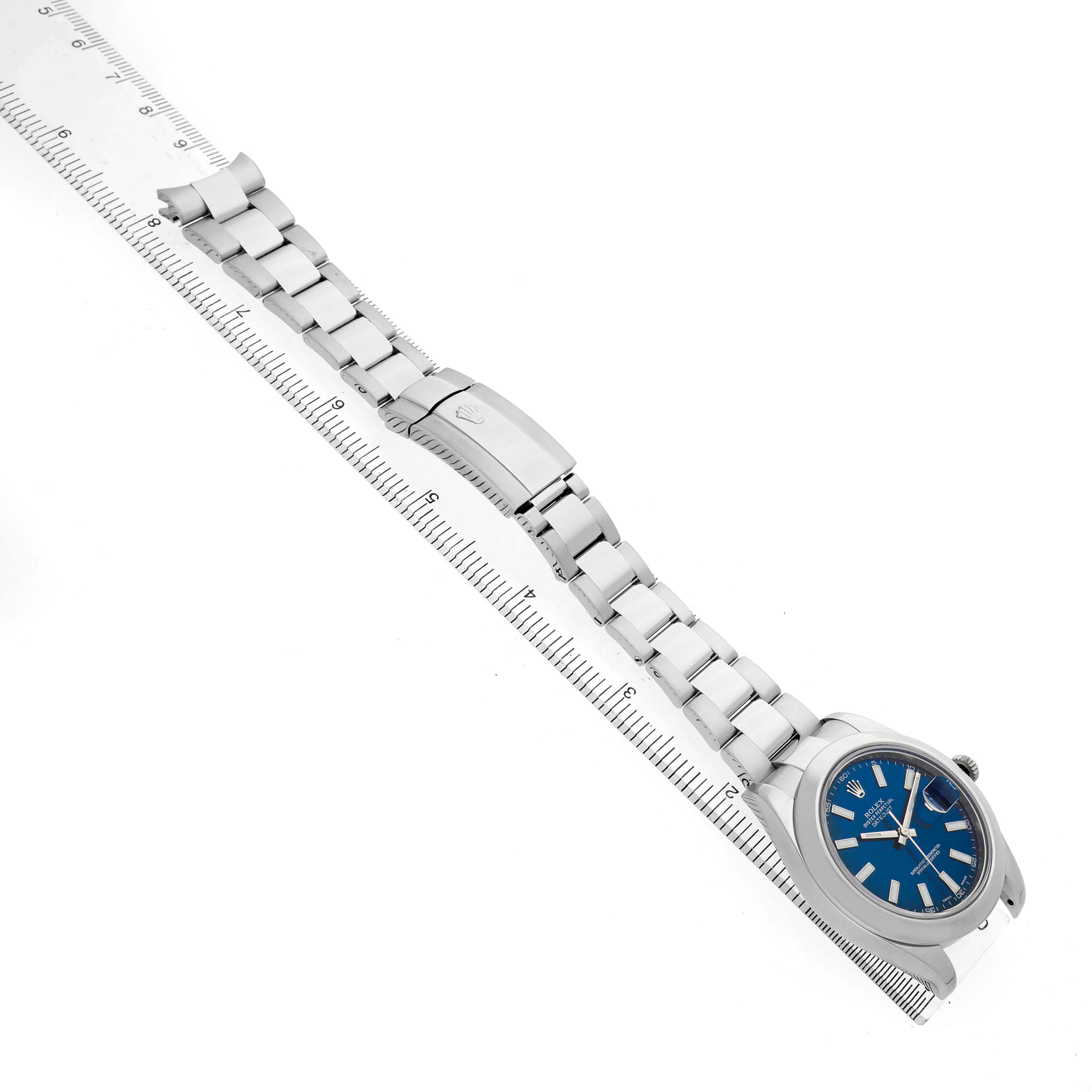 The image shows a Rolex Datejust 41 116300 Men's Stainless Steel Blue Dial watch at a slight angle, highlighting the blue dial, metal bracelet, and clasp on a flat ruler.