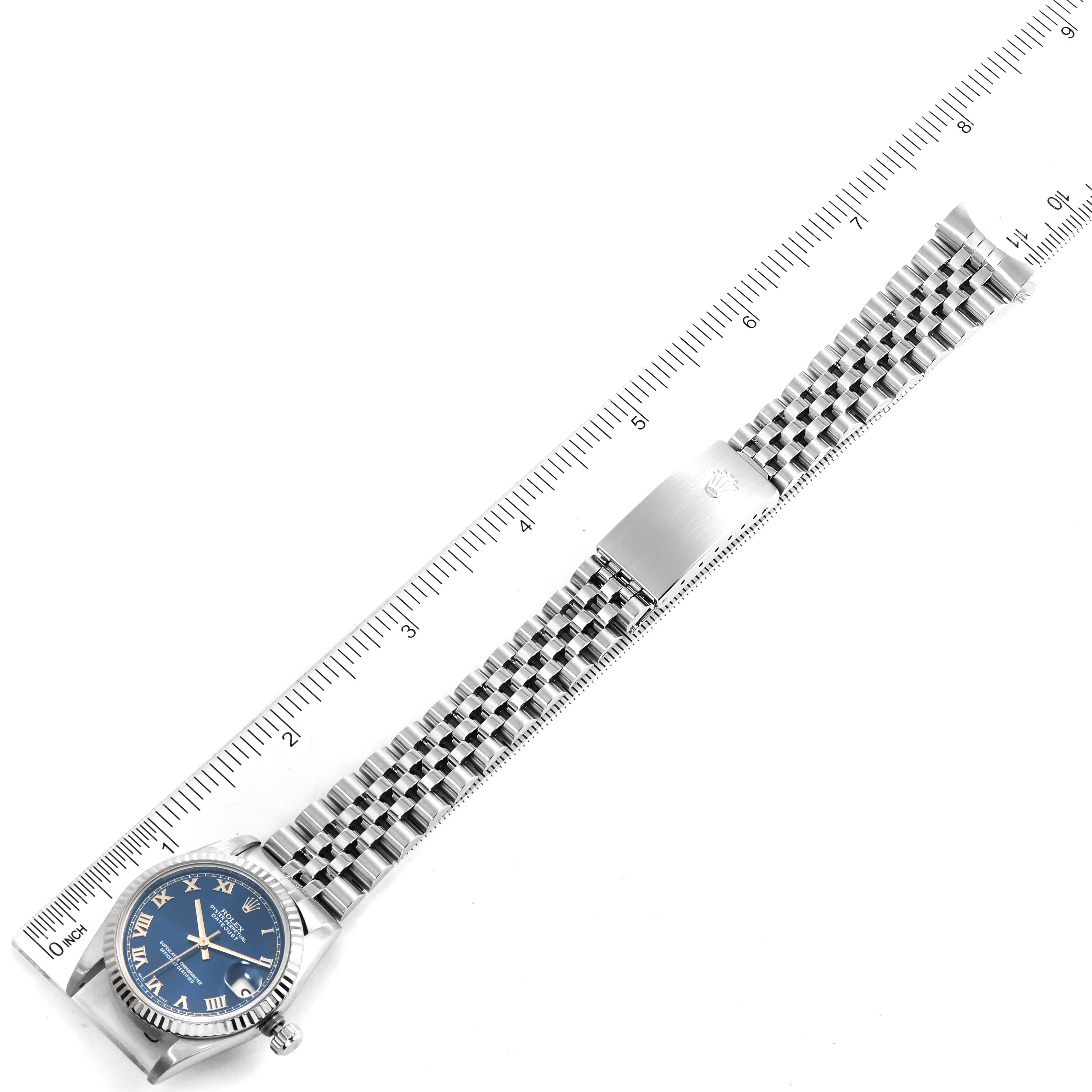 The image shows a Rolex Mid-Size 68274 Women
s Stainless Steel Blue Dial 68274 Women
s Stainless Steel Blue Dial model watch from above, featuring its blue dial and metal bracelet next to a measuring ruler.