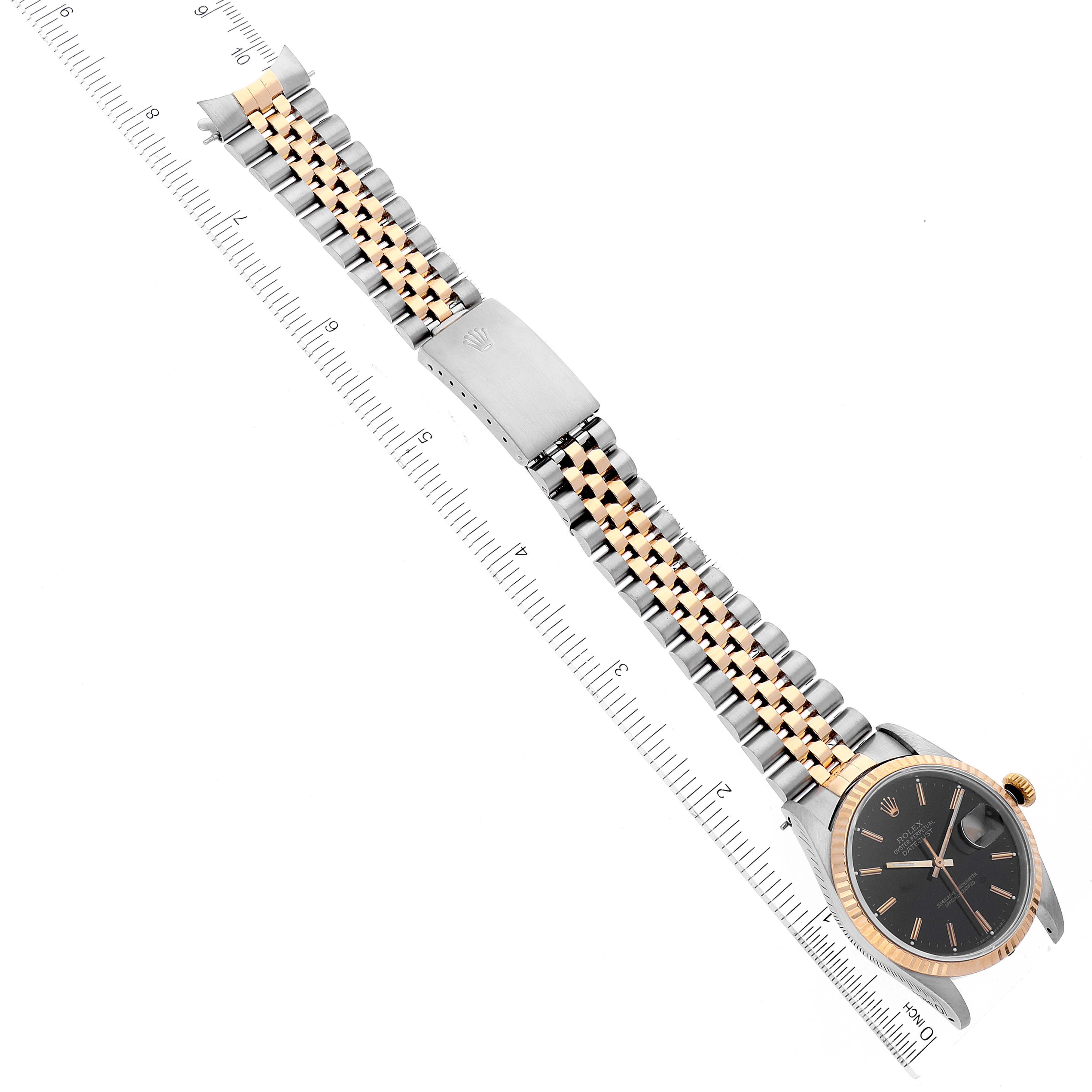 The Rolex Datejust 16233 Men's Steel and Gold (two tone) Black Dial 16233 Men's Steel and Gold (two tone) Black Dial watch is shown at an angle with its full bracelet, face, and clasp clearly visible next to measuring rulers.